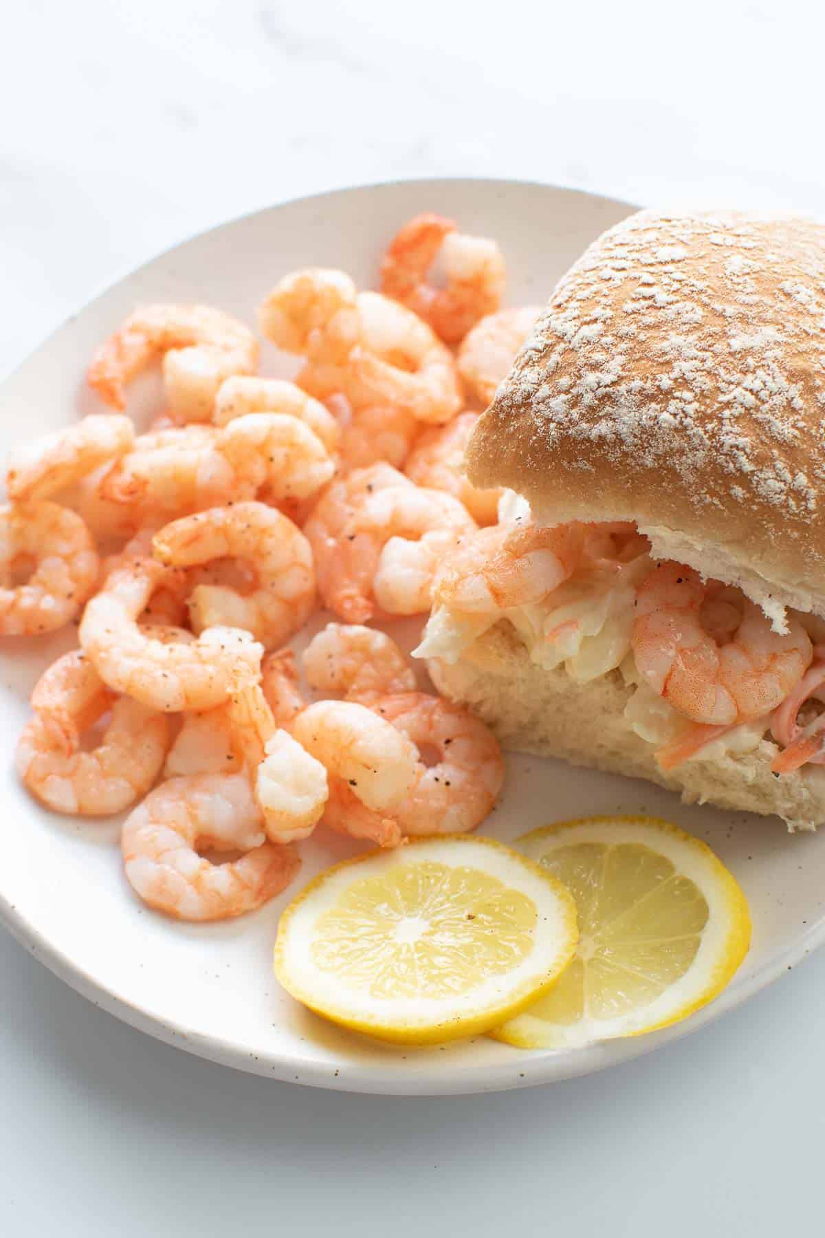 Shrimp sliders with coleslaw and lemon slices.