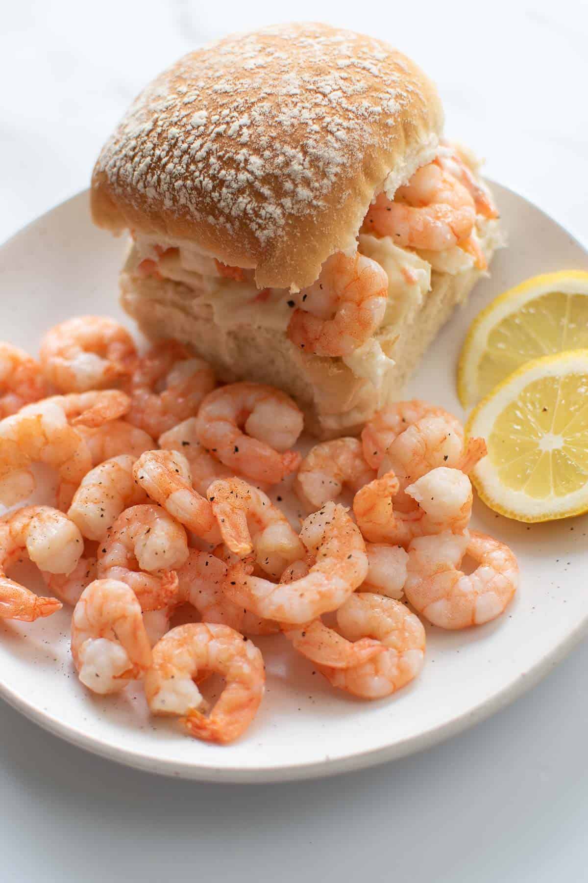 Shrimp on a plate, next to a shrimp and coleslaw slider.