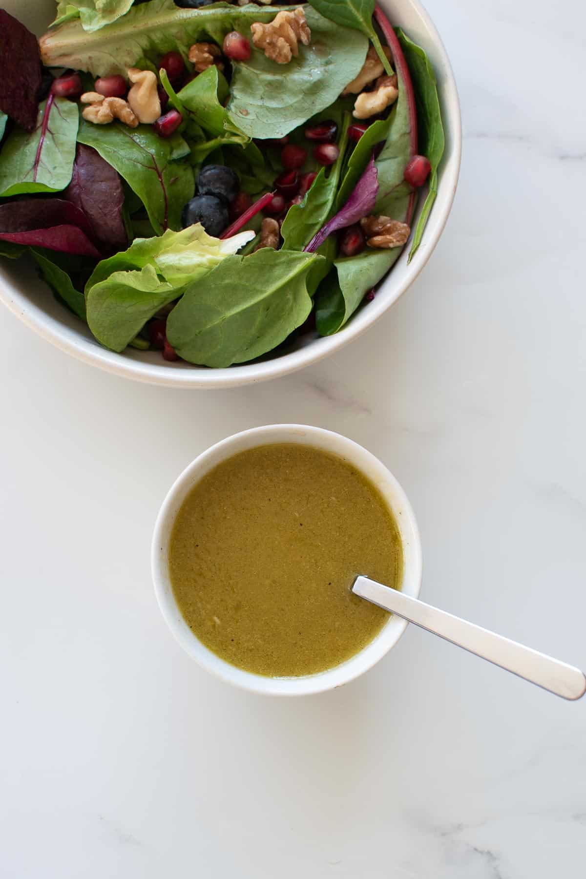 A bowl of apple cider vinaigrette, with salad on the side.