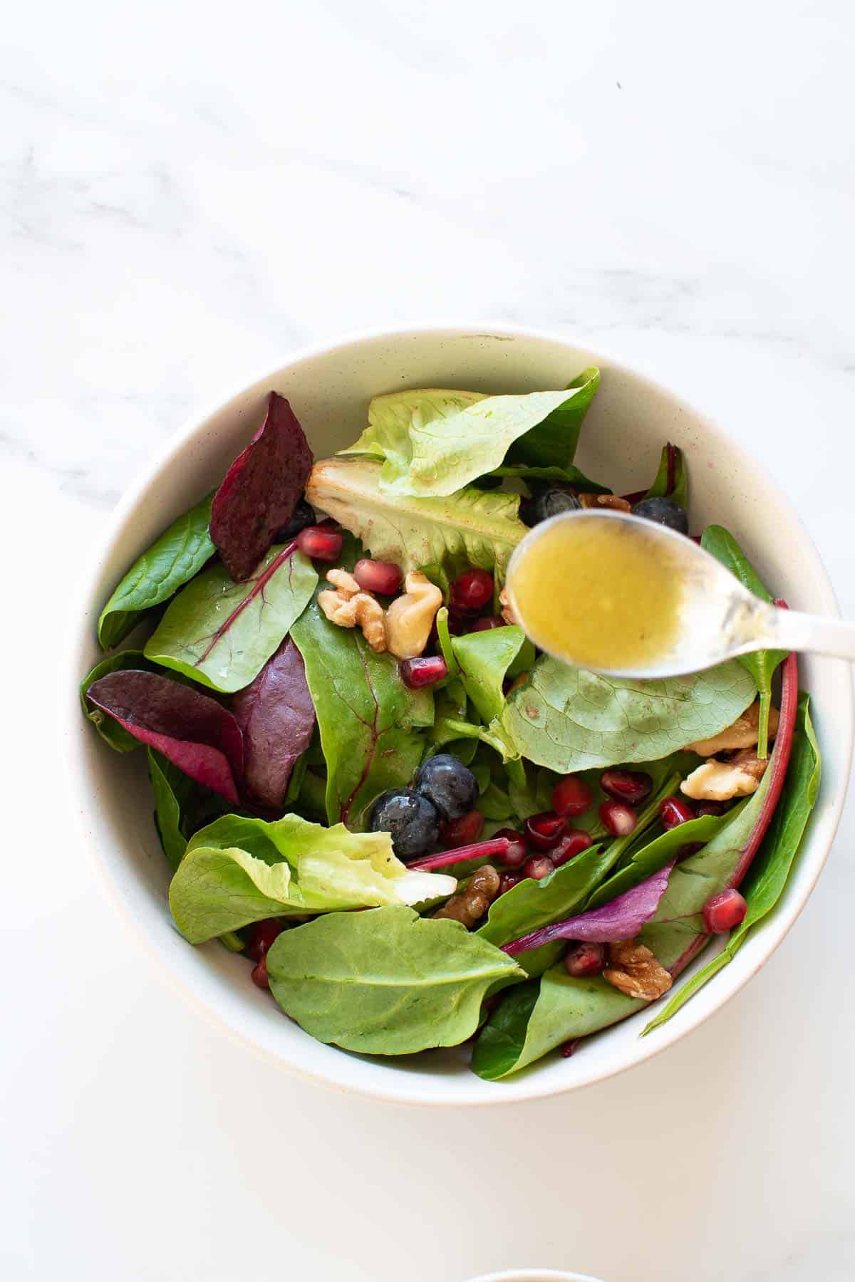 Vinaigrette poured onto a bowl of salad.