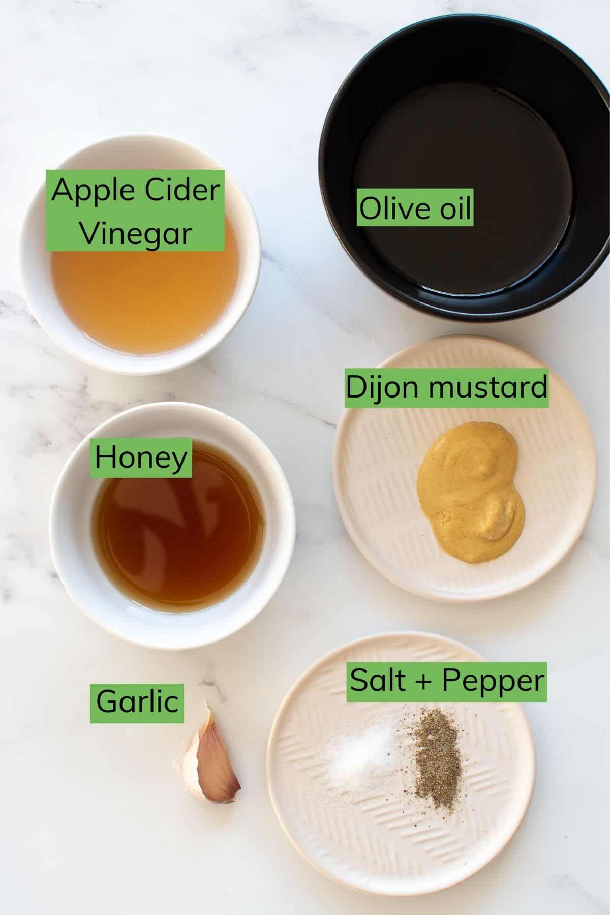 The ingredients required to make apple cider vinaigrette laid out on a table.