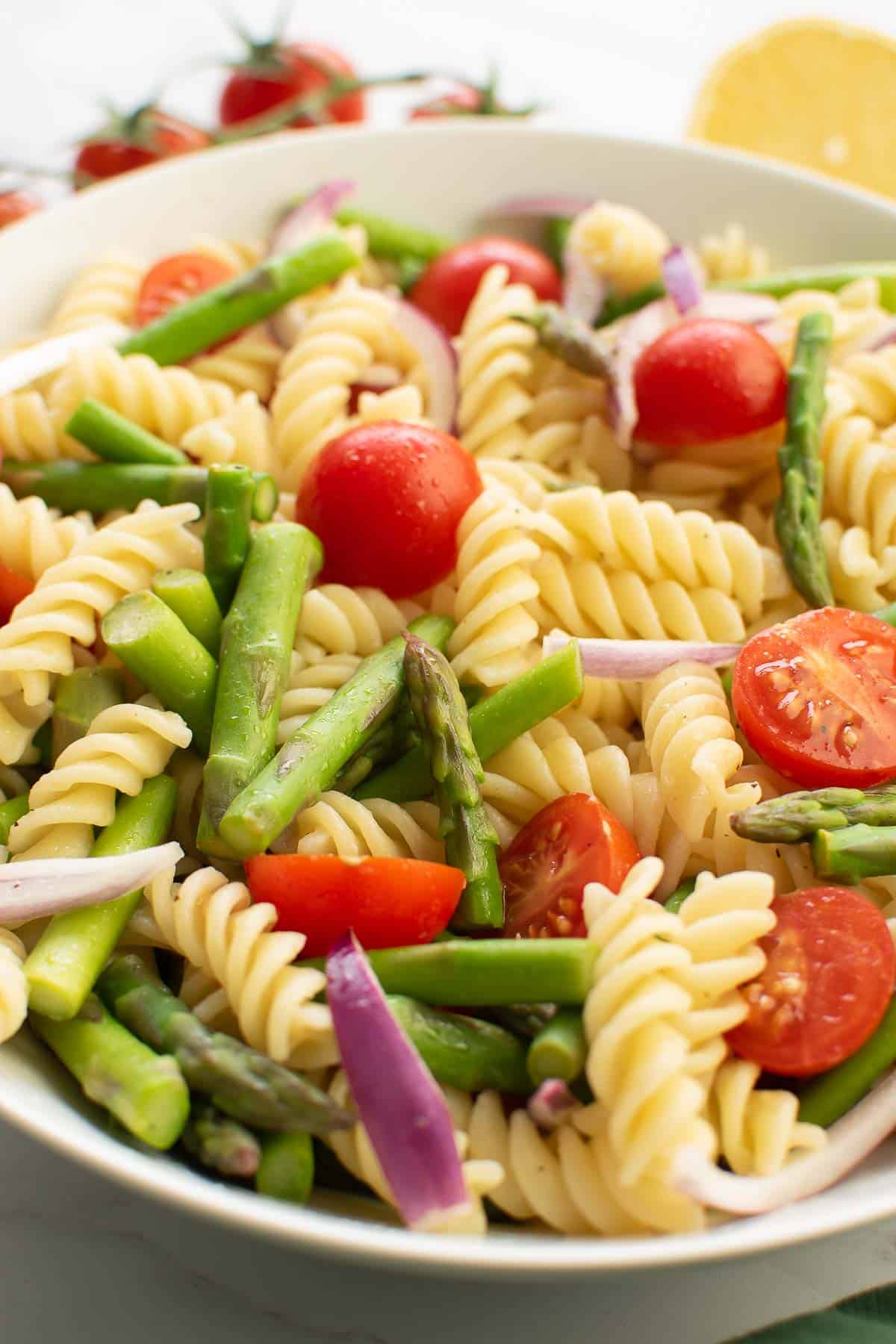 Close up of asparagus, pasta and tomatoes in a bowl.