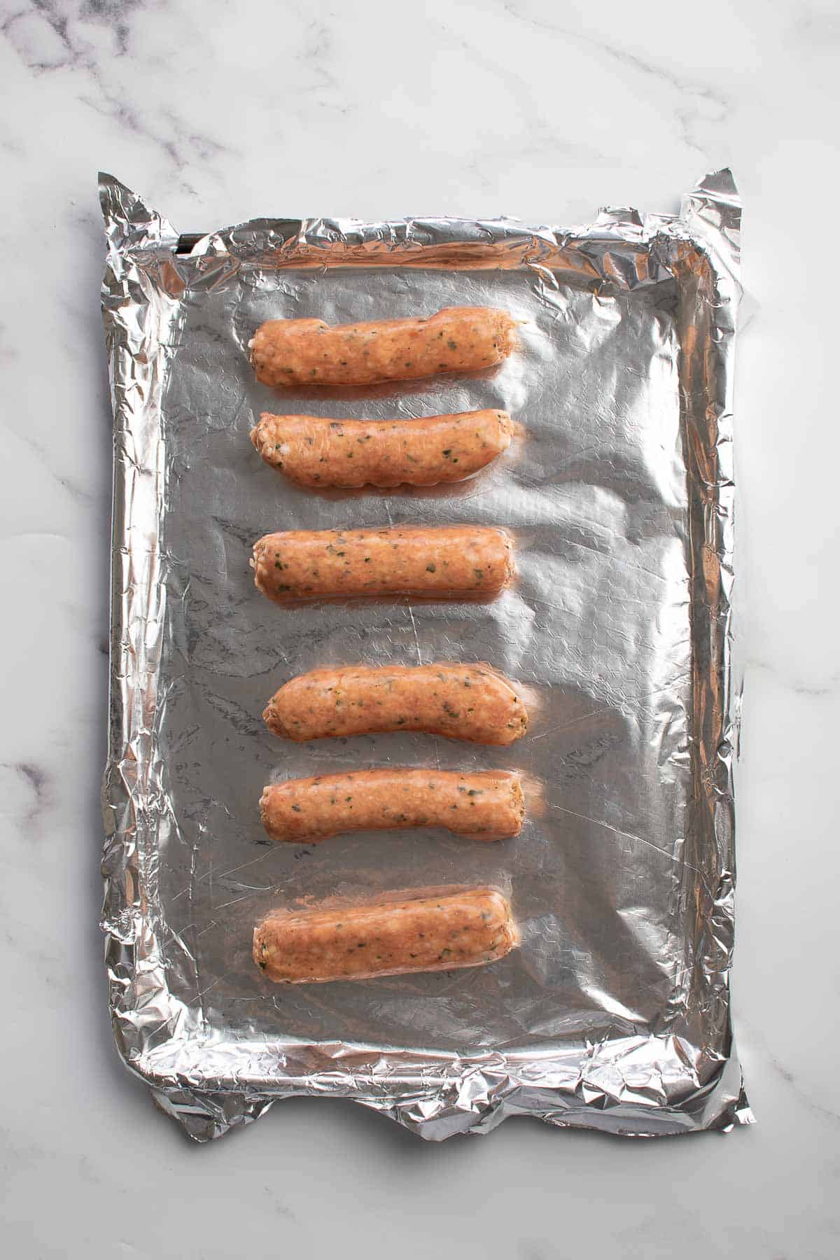 Raw sausages on a baking sheet.