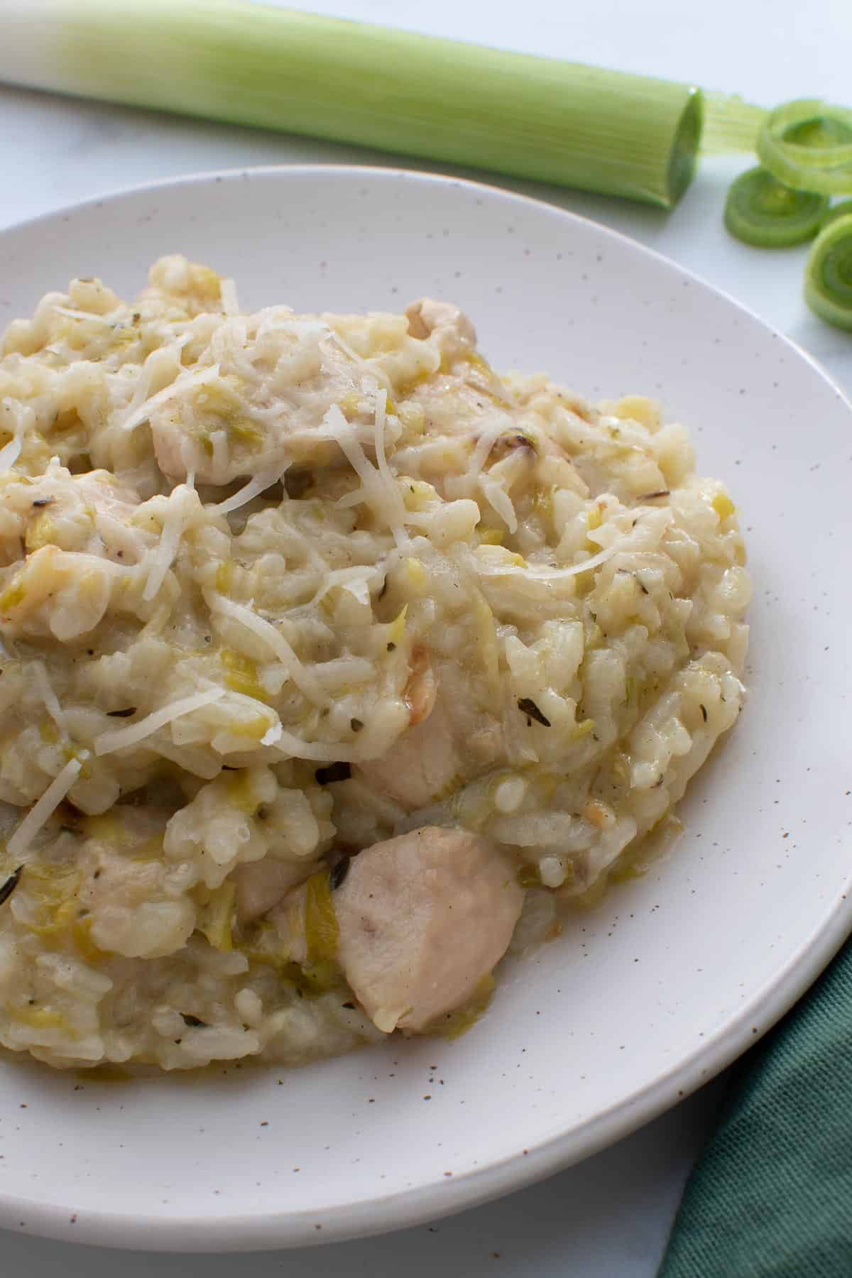 Creamy chicken risotto with leek in the background.