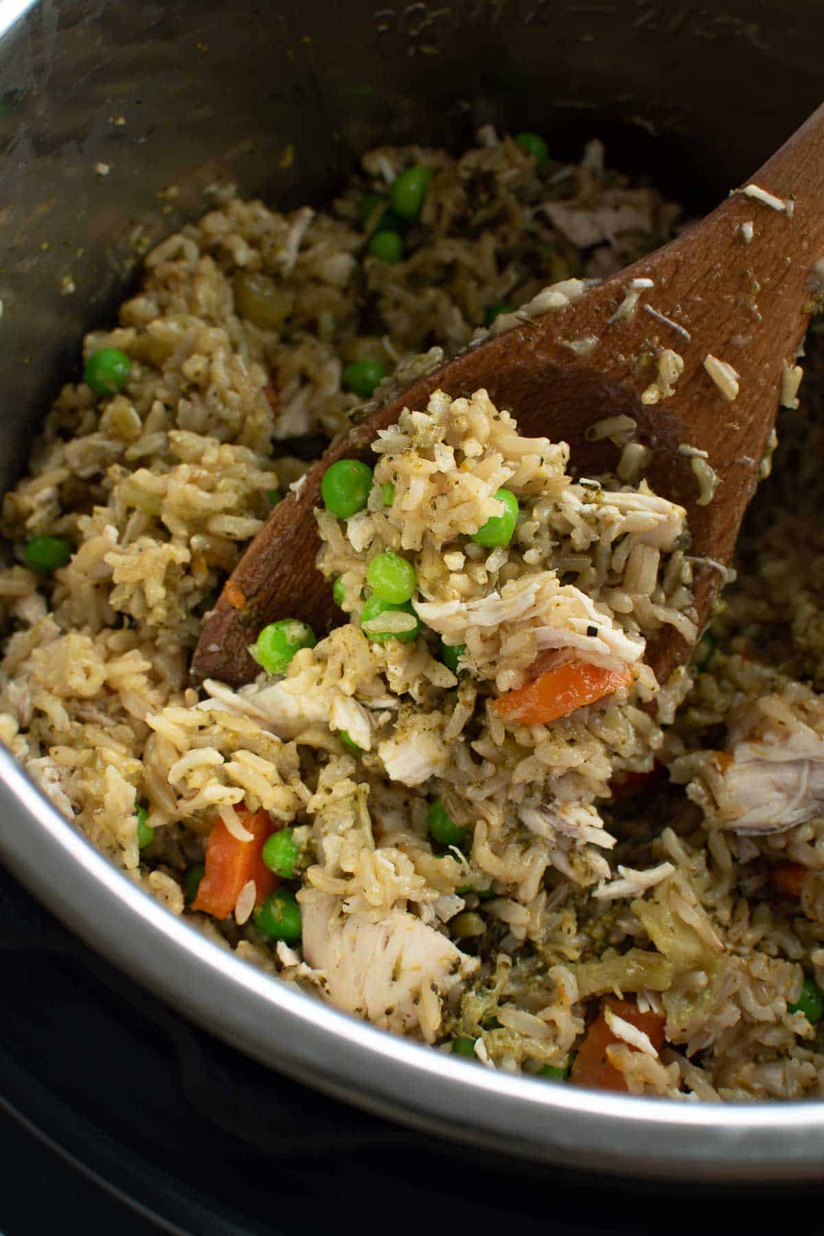 Chicken and rice in instant pot, with a spoon lifting up a serving.