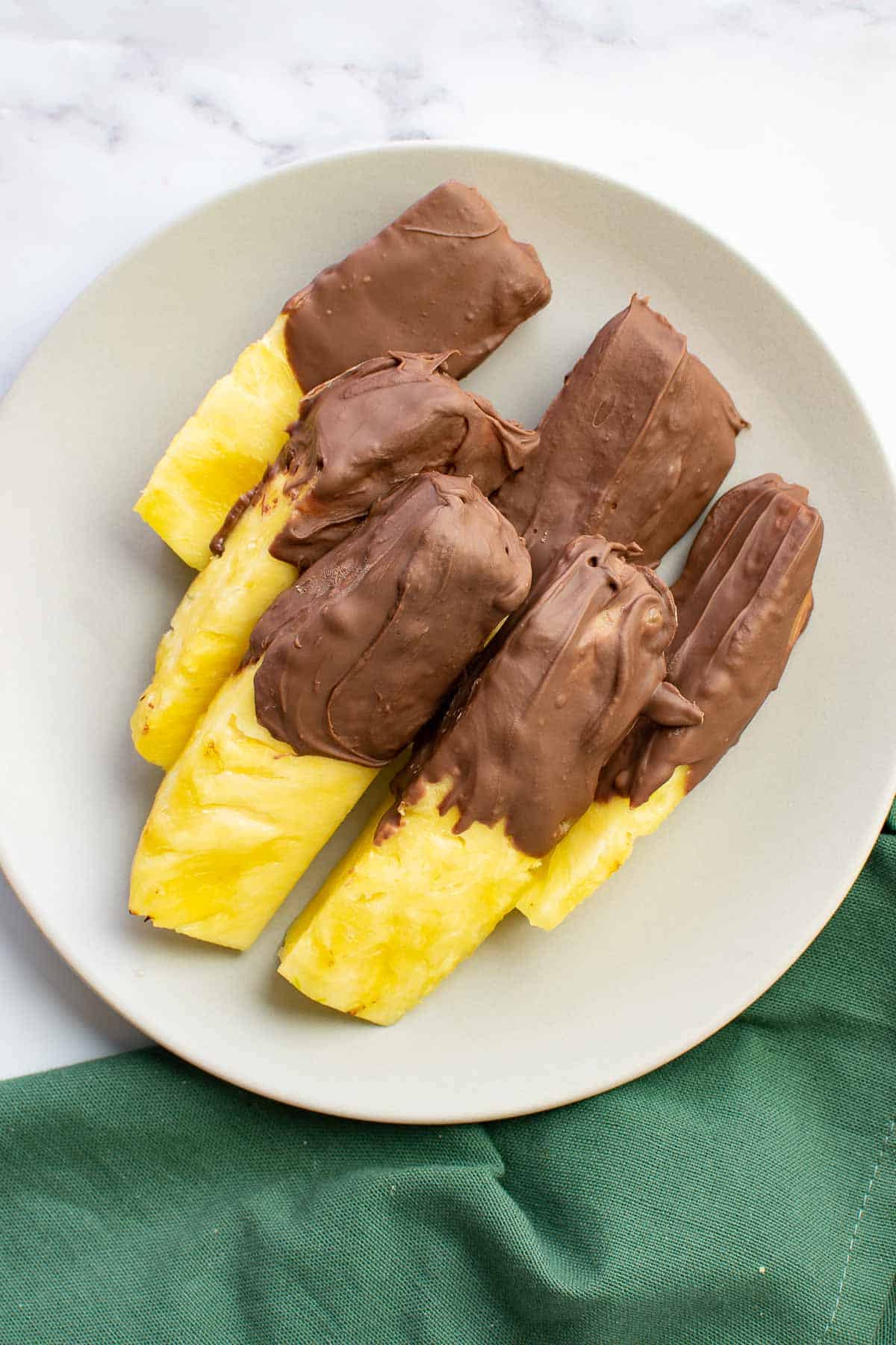 Pineapple slicks with melted chocolate on a plate.