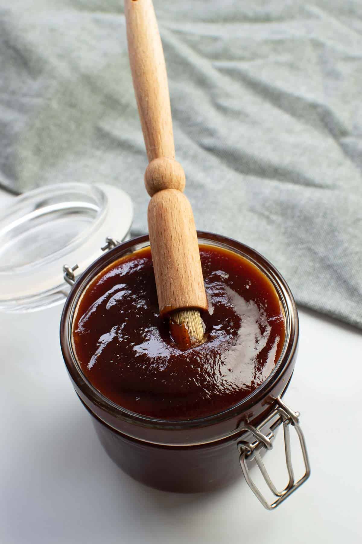 Sweet BBQ sauce in a jar with a brush dipped into it.