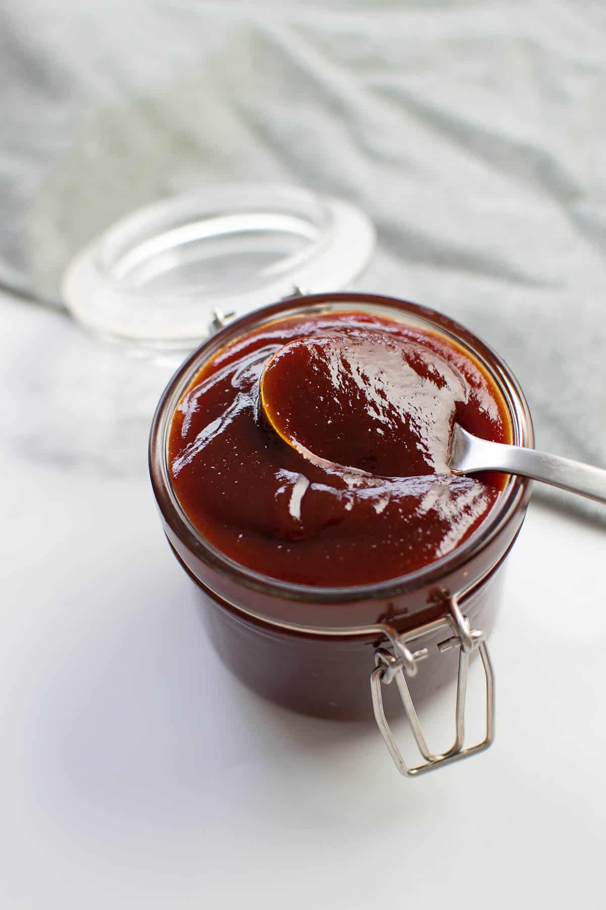 A bowl of BBQ sauce with a spoon.