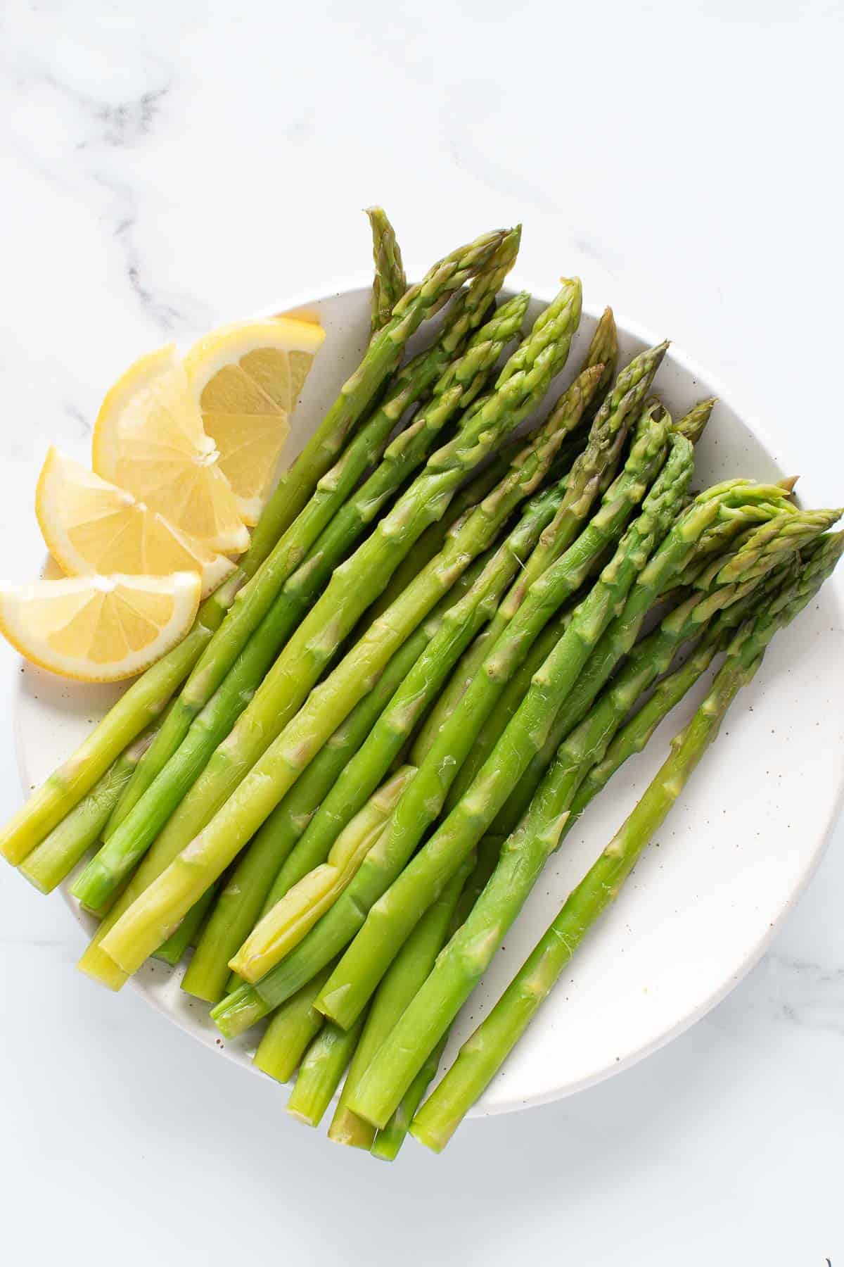 Steamed asparagus with lemon on a plate.