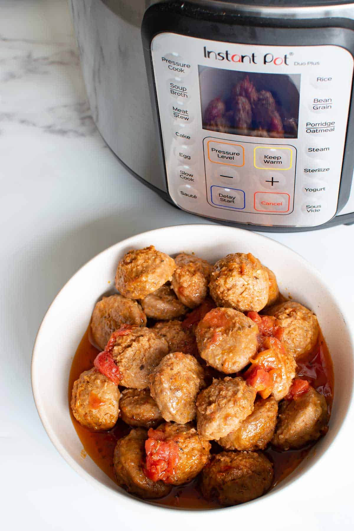 A bowl of meatballs in front of an instant pot.