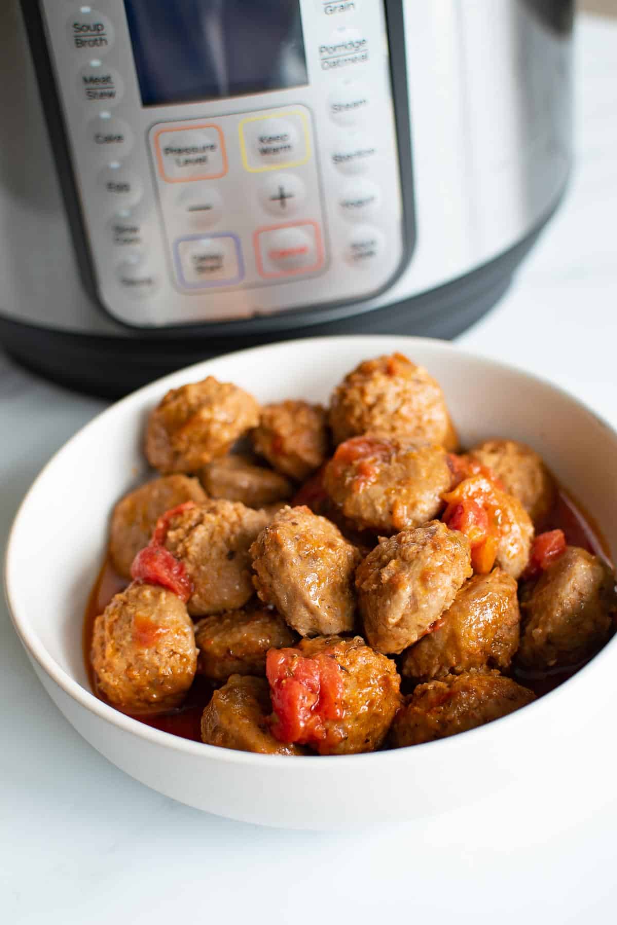 A bowl of meatballs in front of an instant pot.