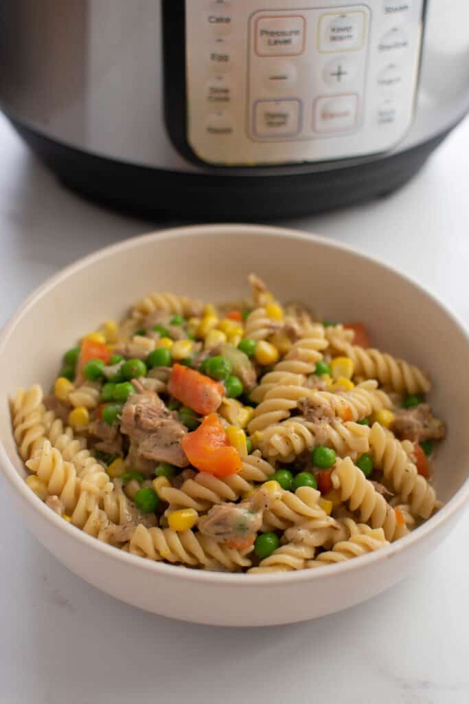 Tuna casserole in a bowl, with an instant pot in the background.