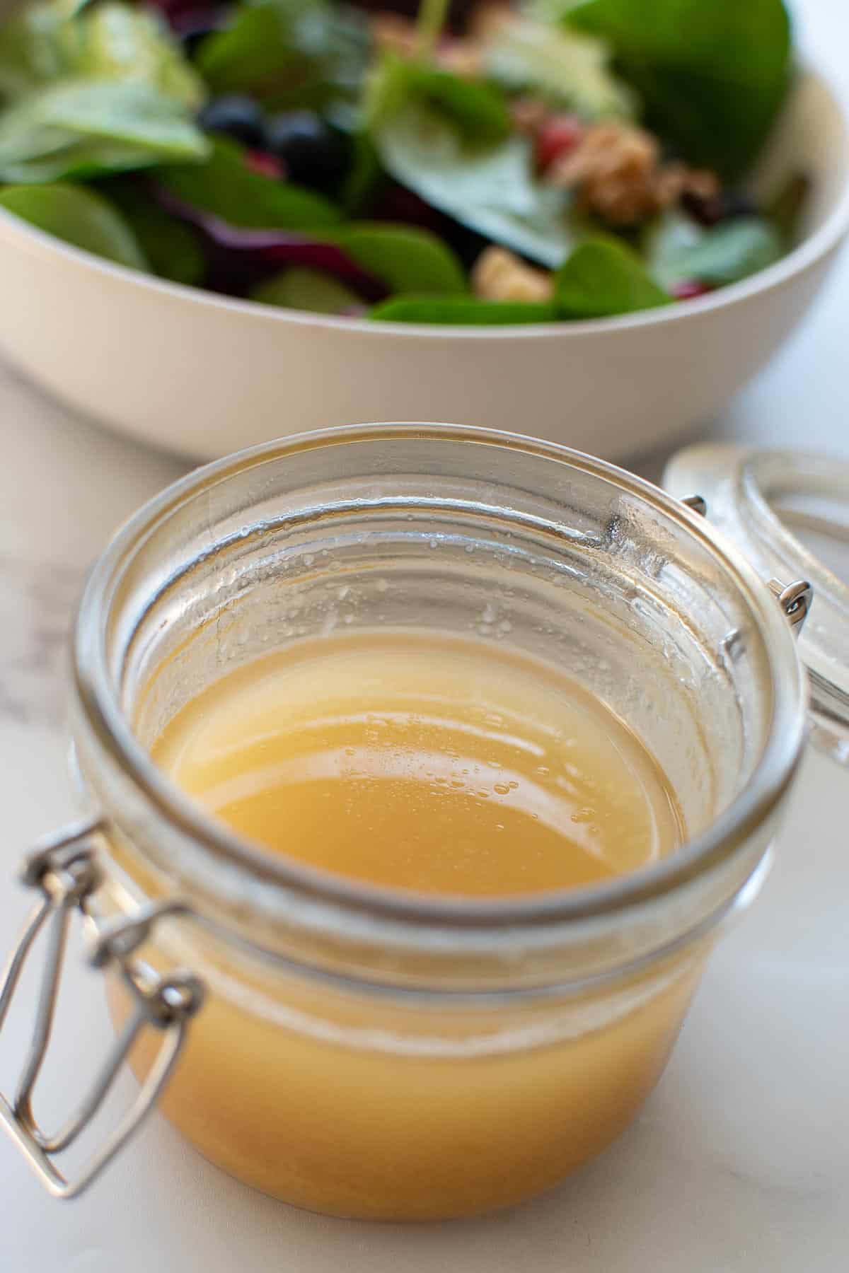 Maple vinaigrette in a jar, with salad in the background.