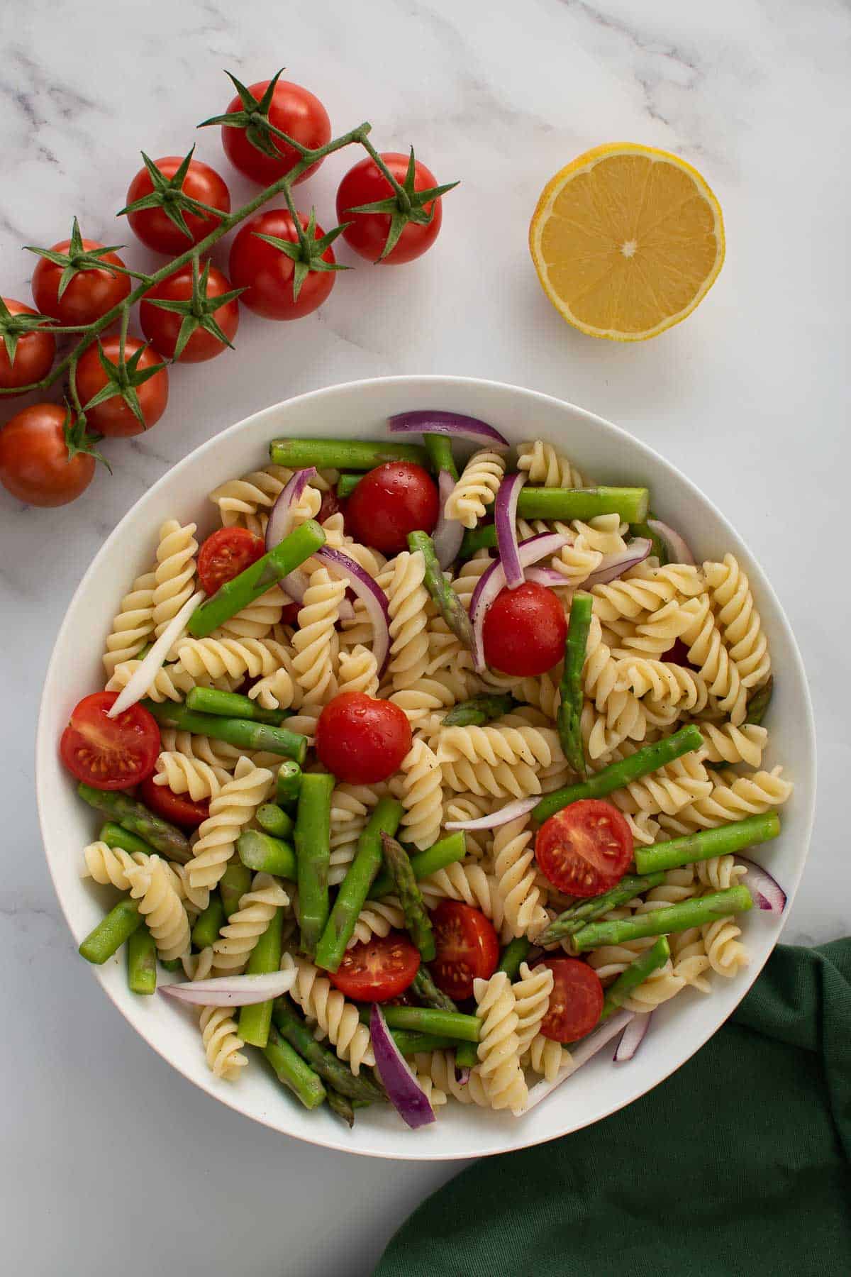 Pasta salad with asparagus and tomatoes in a bowl.