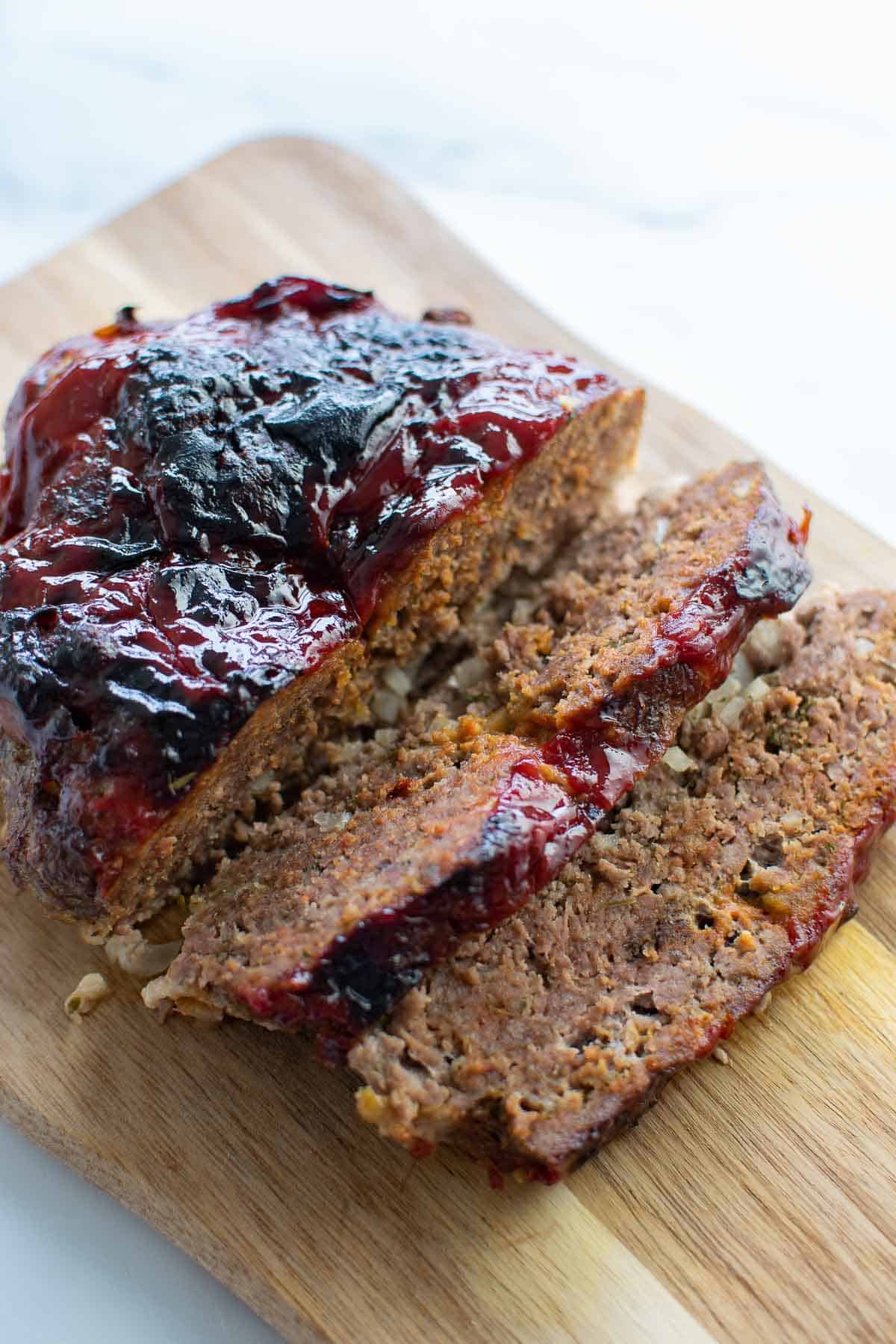 Sliced air fried meatloaf on a wooden board.