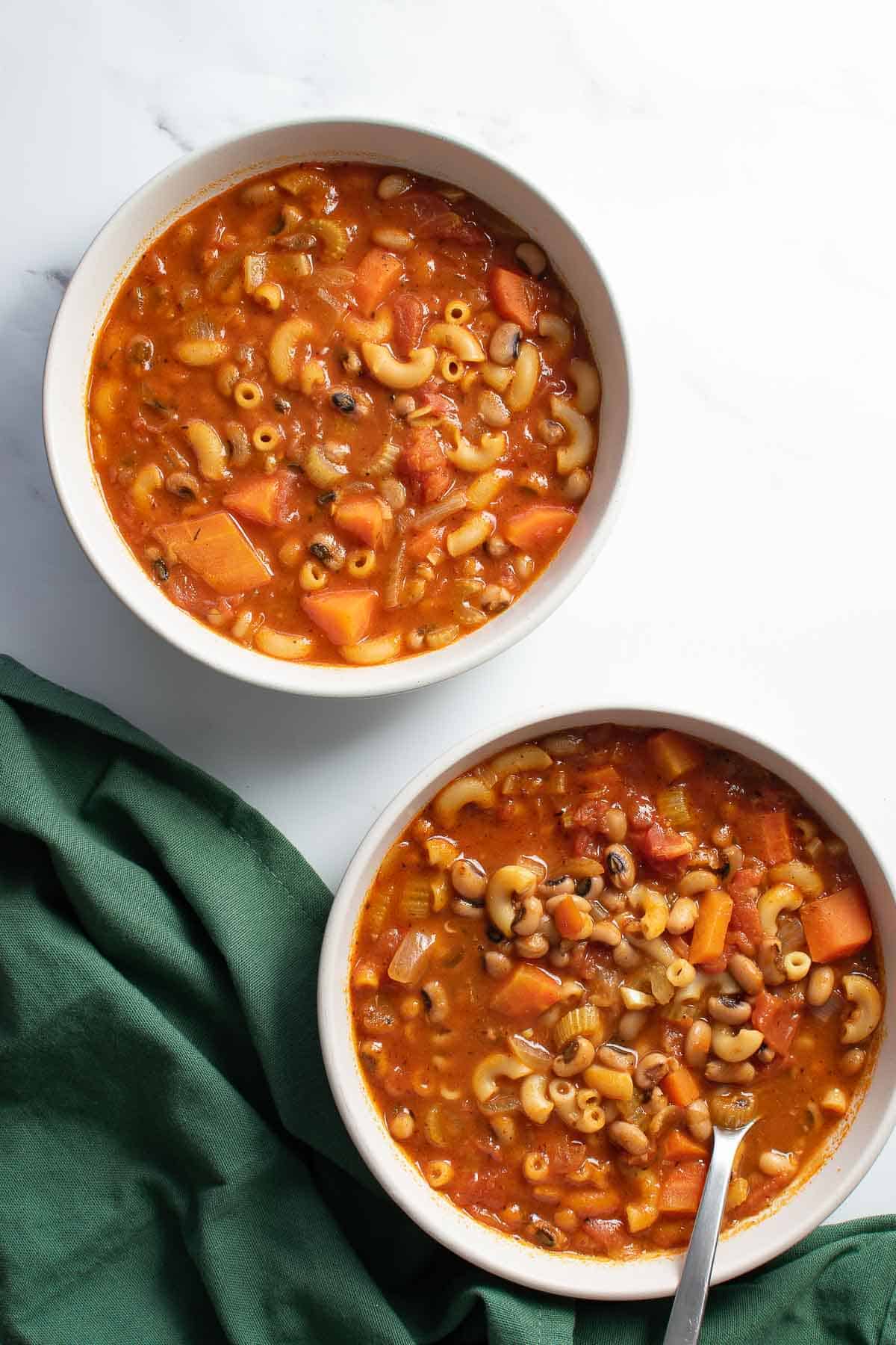 Two bowls of soup with black eyed peas on a table.