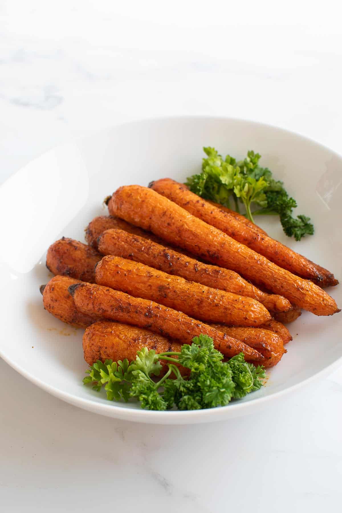 Spicy roast carrots with parsley in a bowl.