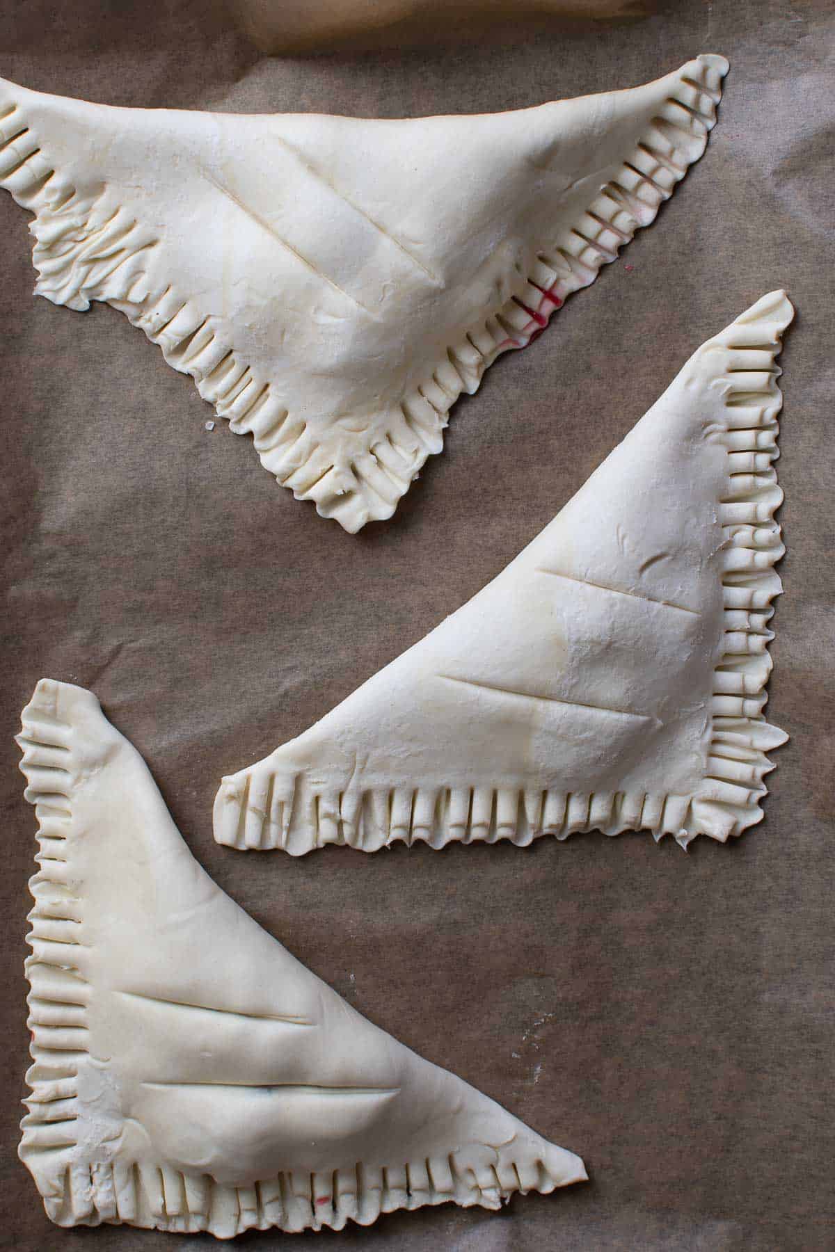 Uncooked turnovers on a baking sheet.