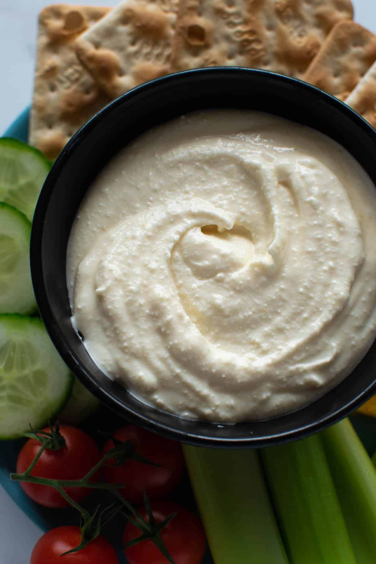 Whipped feta dip in a bowl with vegetables on the side.