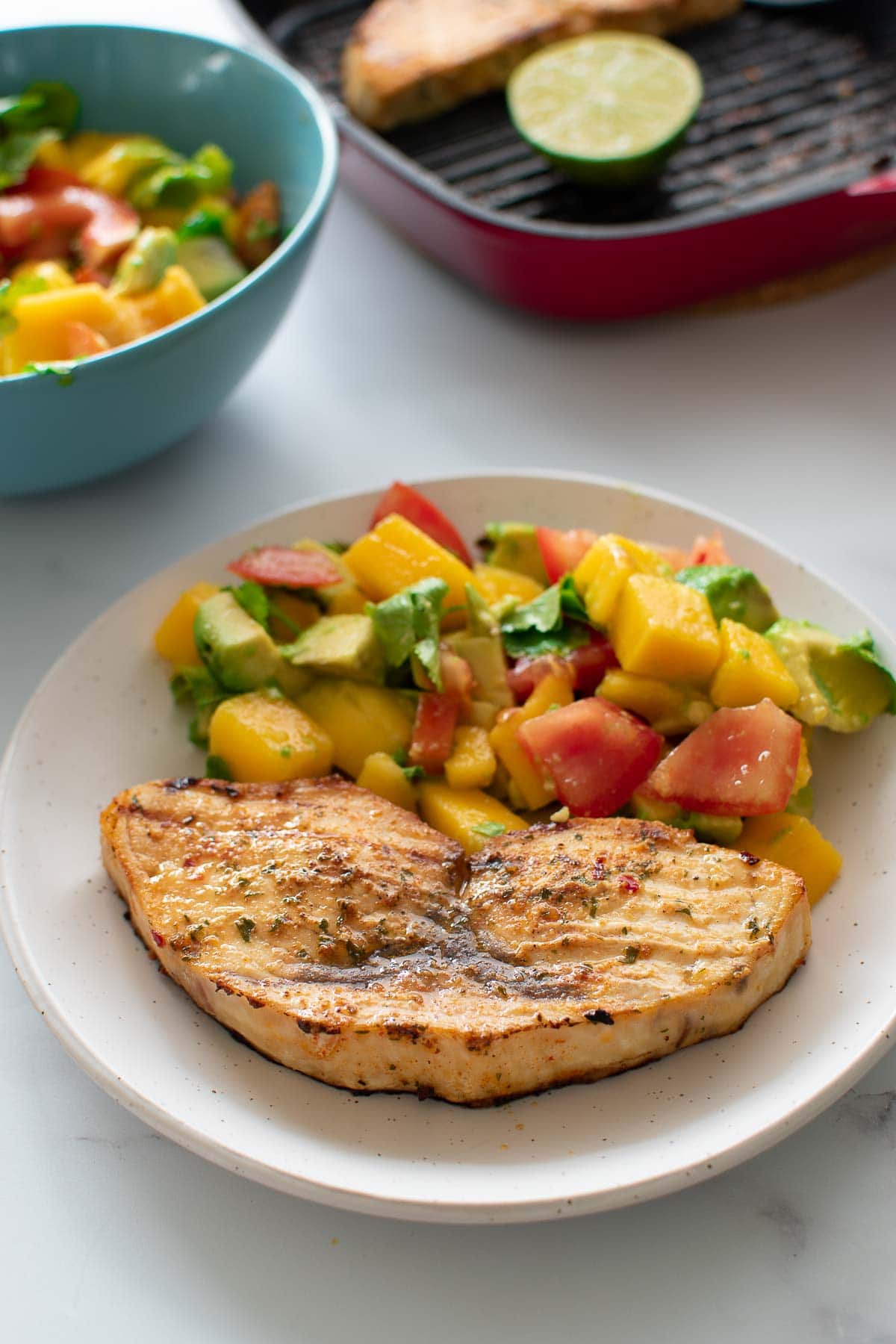 Swordfish served with salad, with a baking dish in the background.