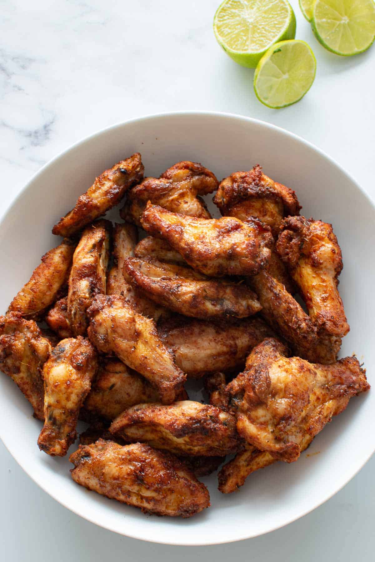 Crispy Cajun wings with lime wedges on the side.