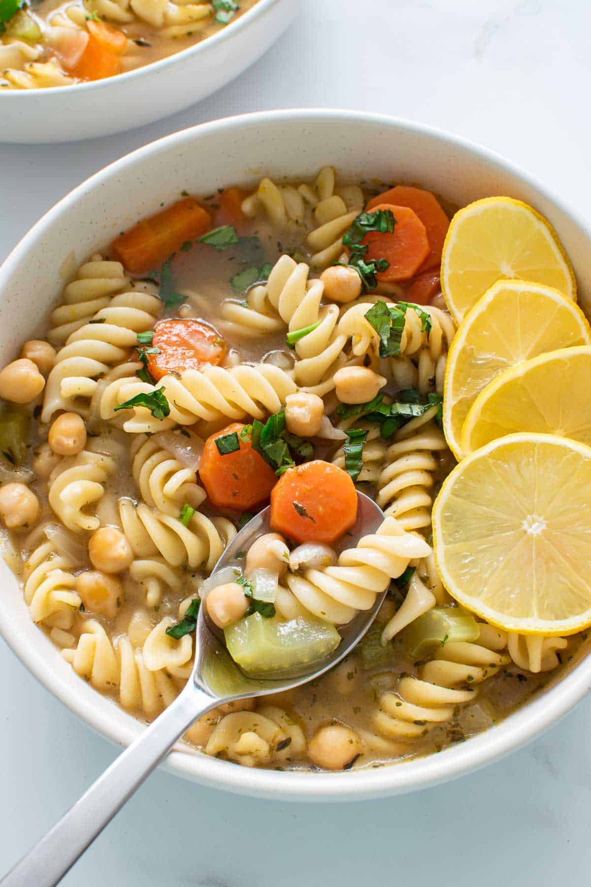 Chickpea pasta soup, with a spoon lifting up a serving.