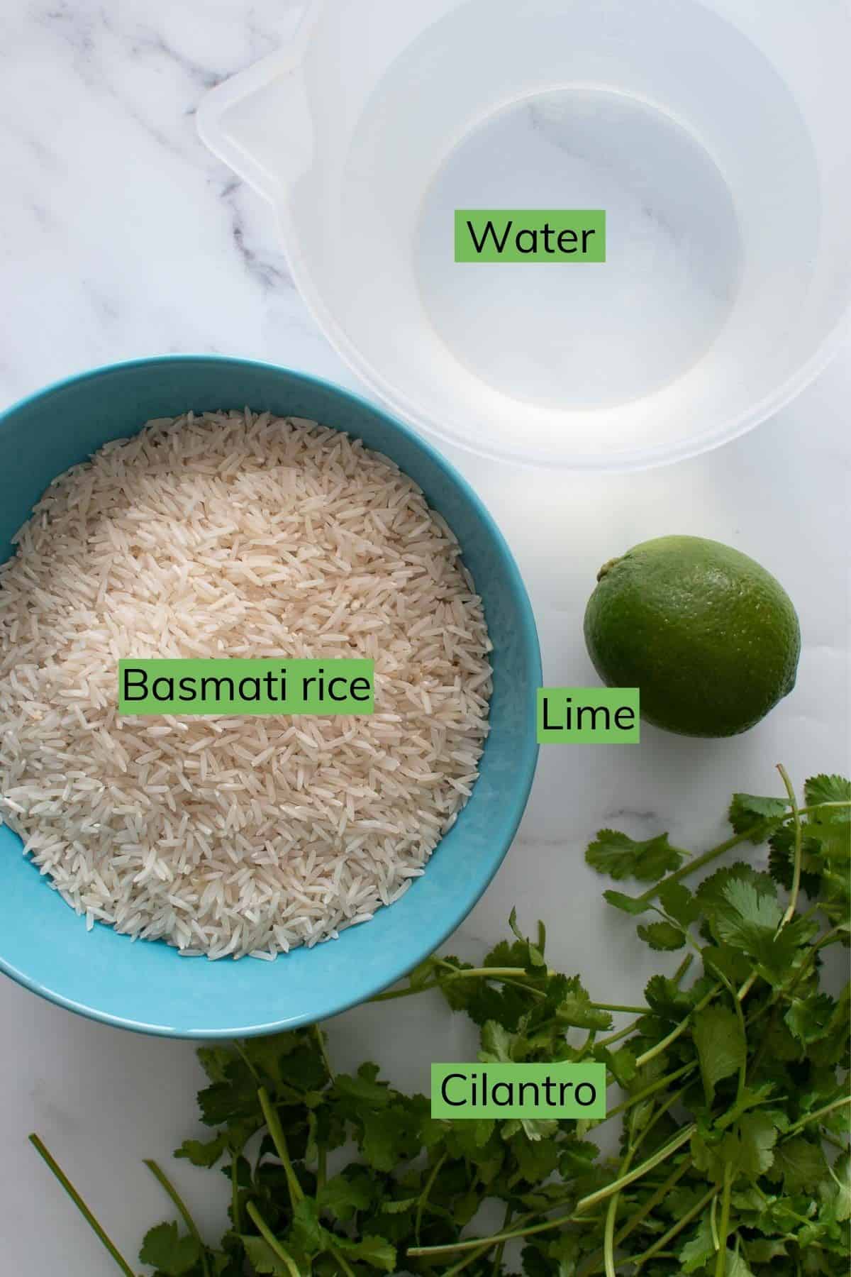 Rice, water, cilantro and lime laid out on a table.