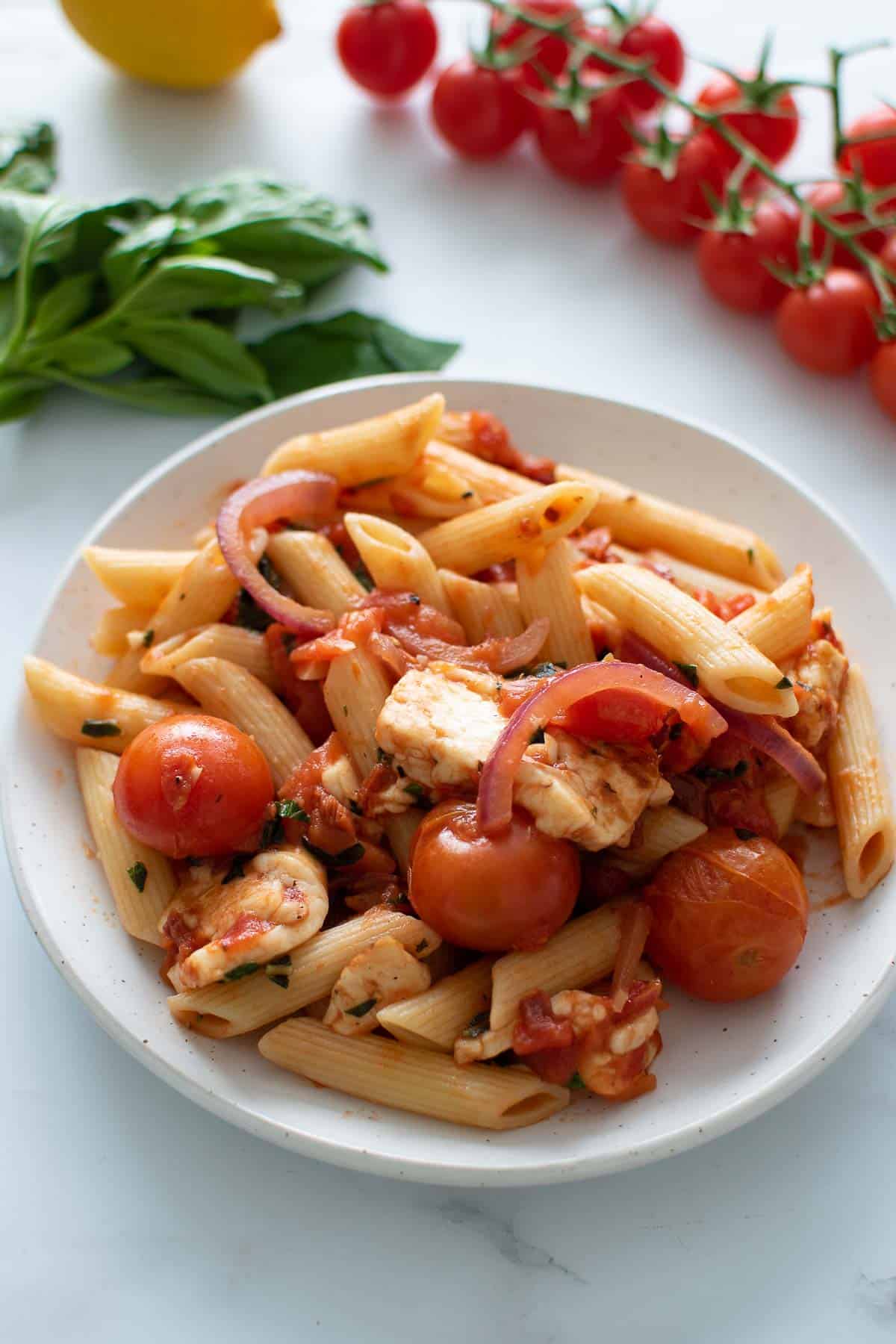 A plate of pasta with halloumi and tomatoes.