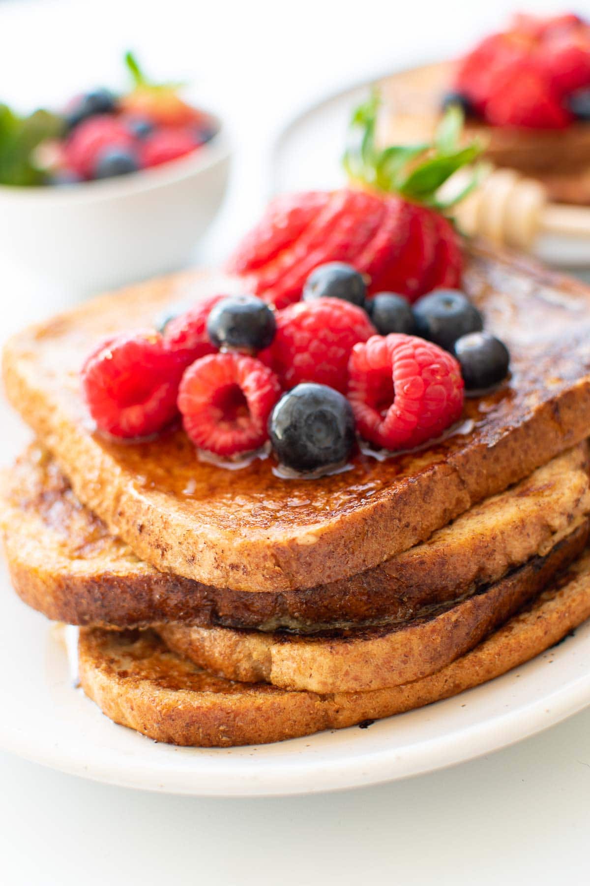 Close up of a stack of French toast with raspberries and blueberries.