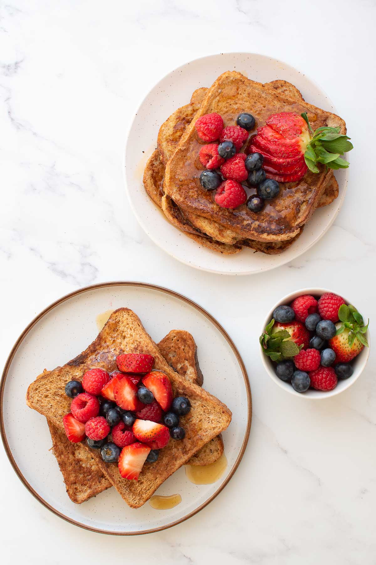 Two plates of French toast with berries.