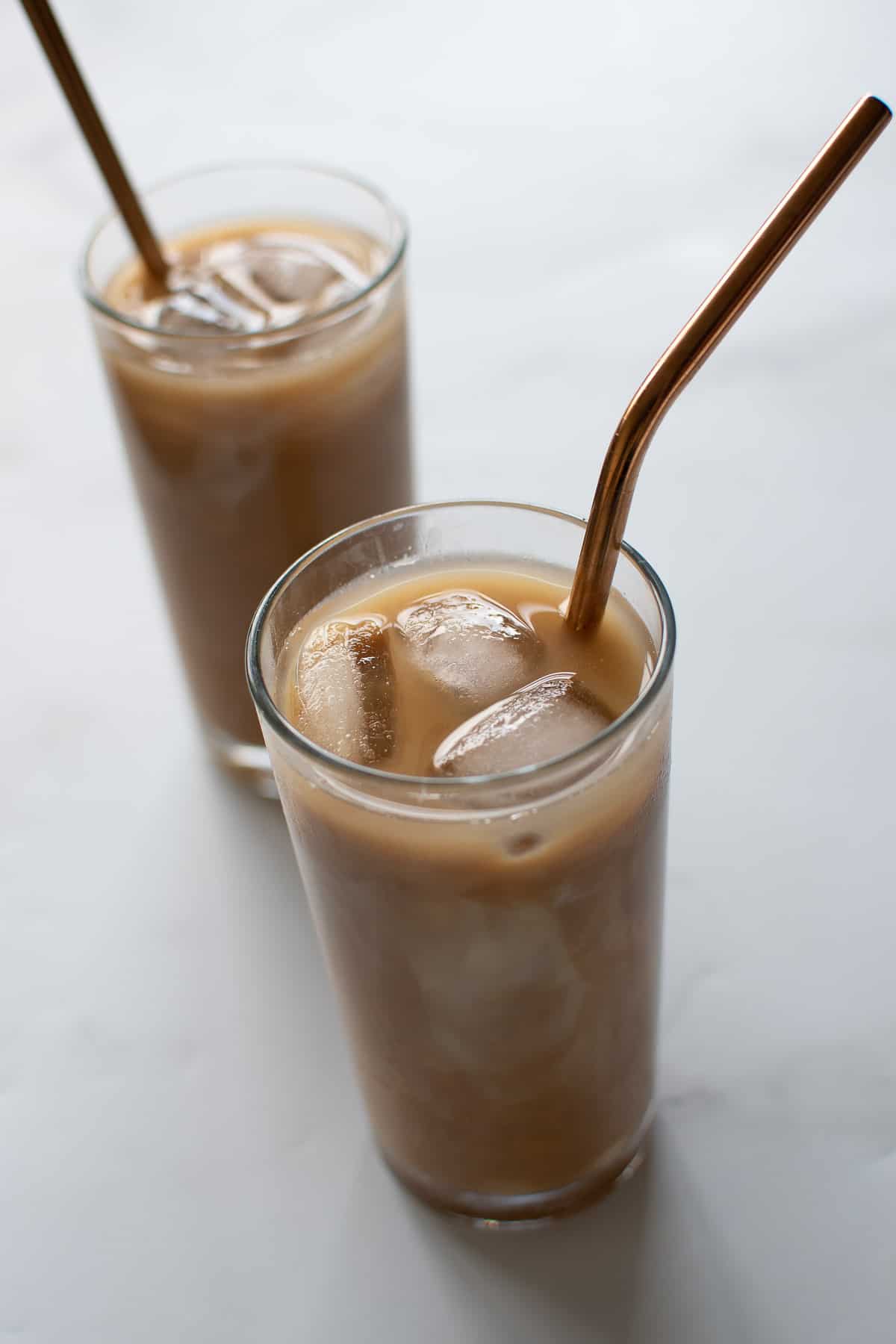 Glasses of iced coffee with caramel, with metal straws.