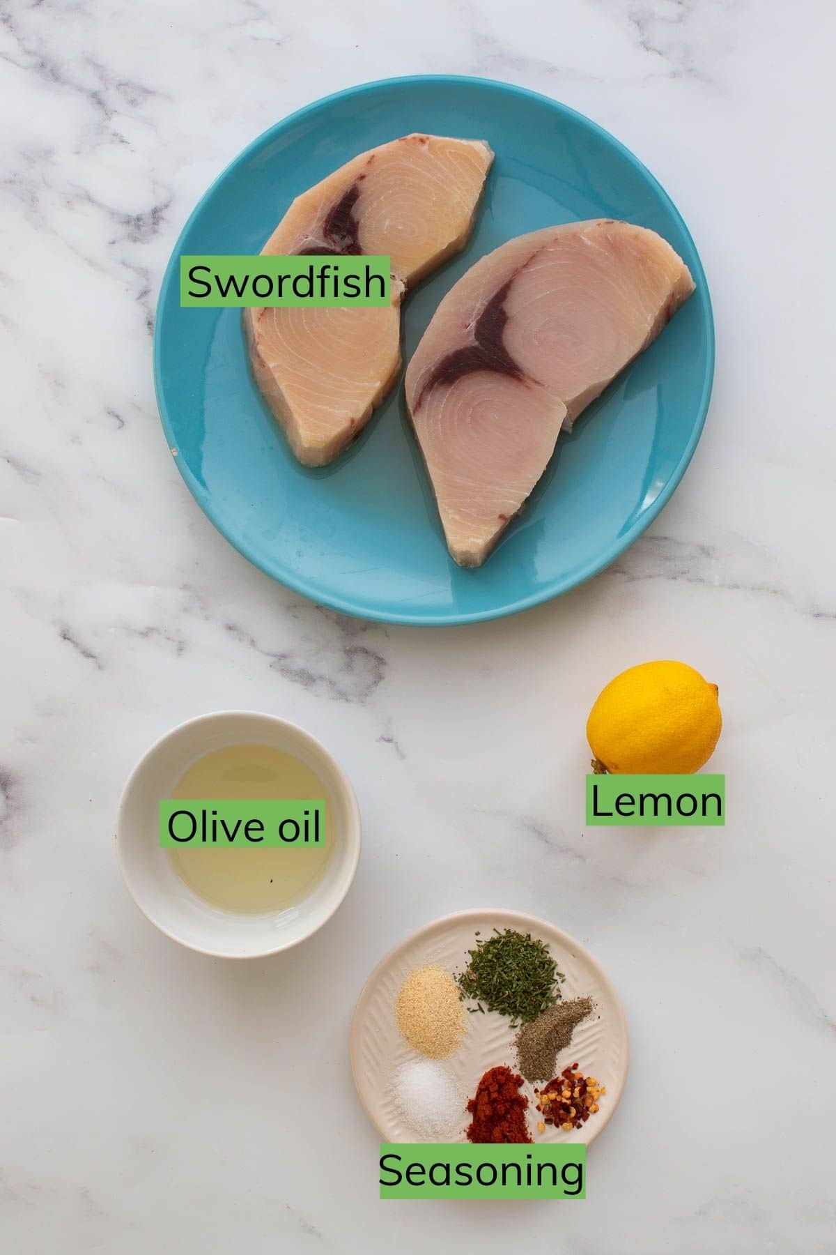 Swordfish, olive oil, lemon and seasoning on a table.