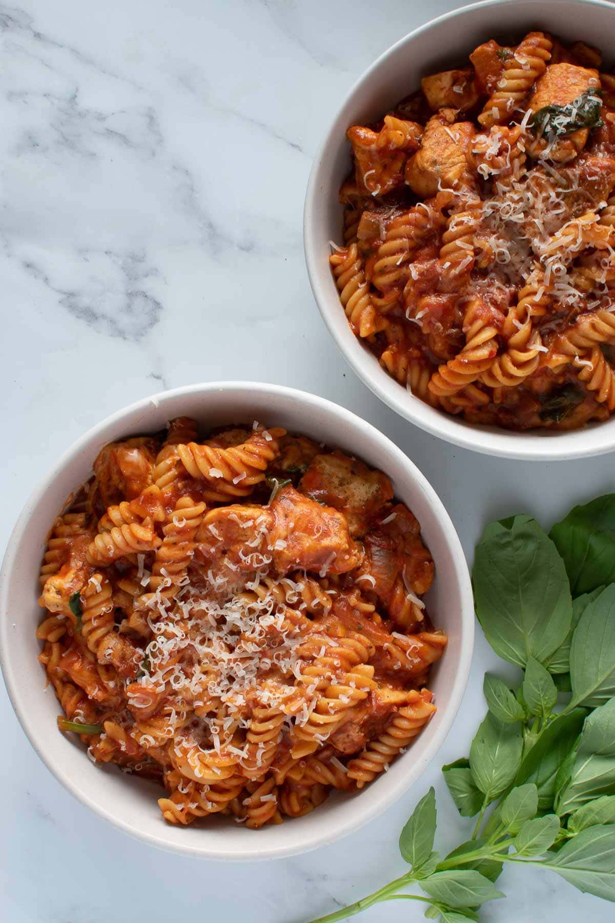 Two bowls of pasta with chicken.