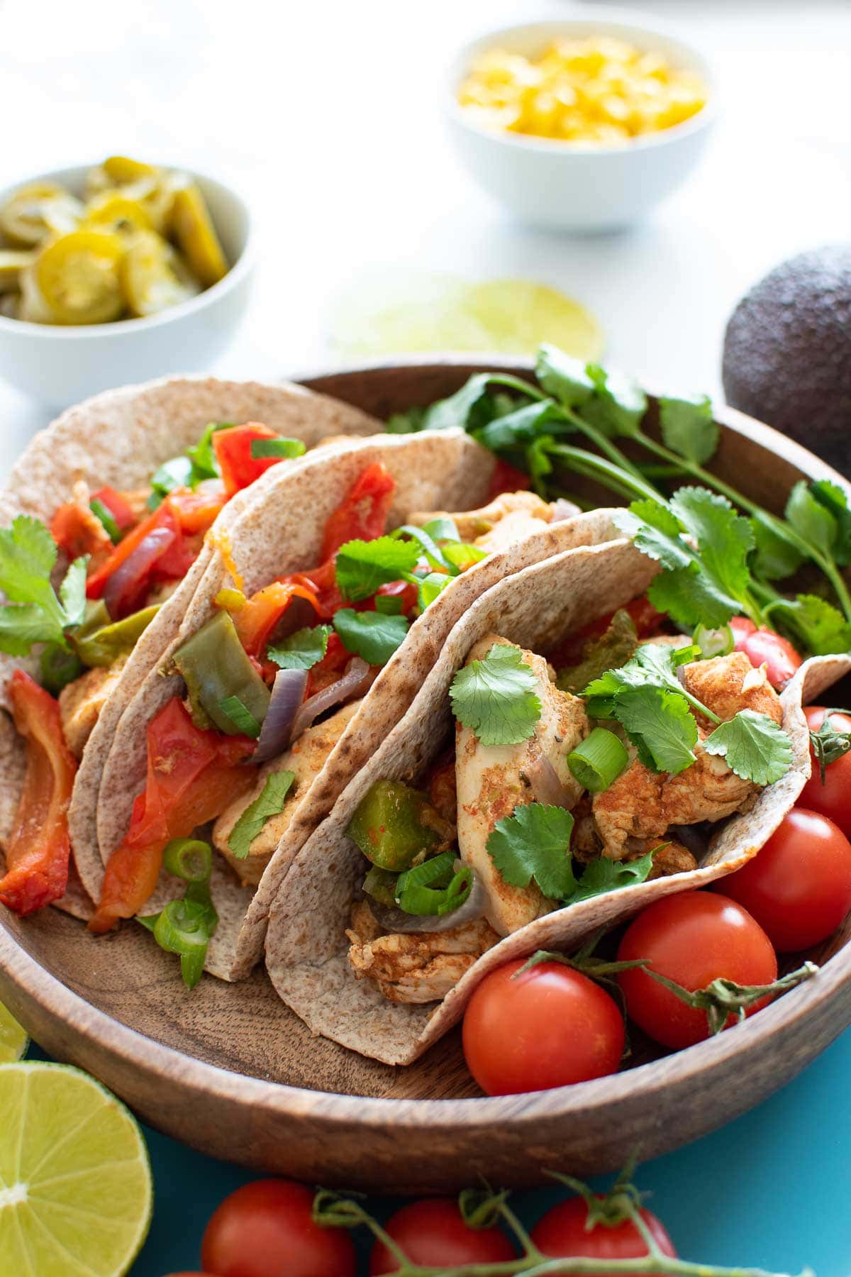 A plate of fajitas with lime, cilantro and tomatoes on the side.