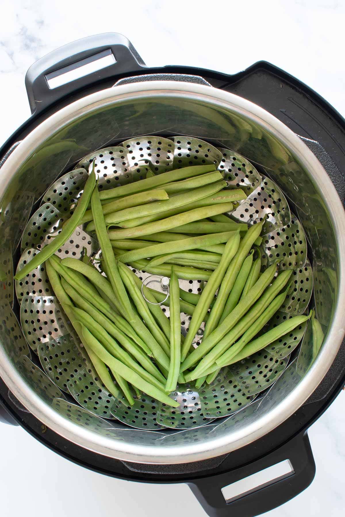 Close up image of green beans in a pressure cooker.