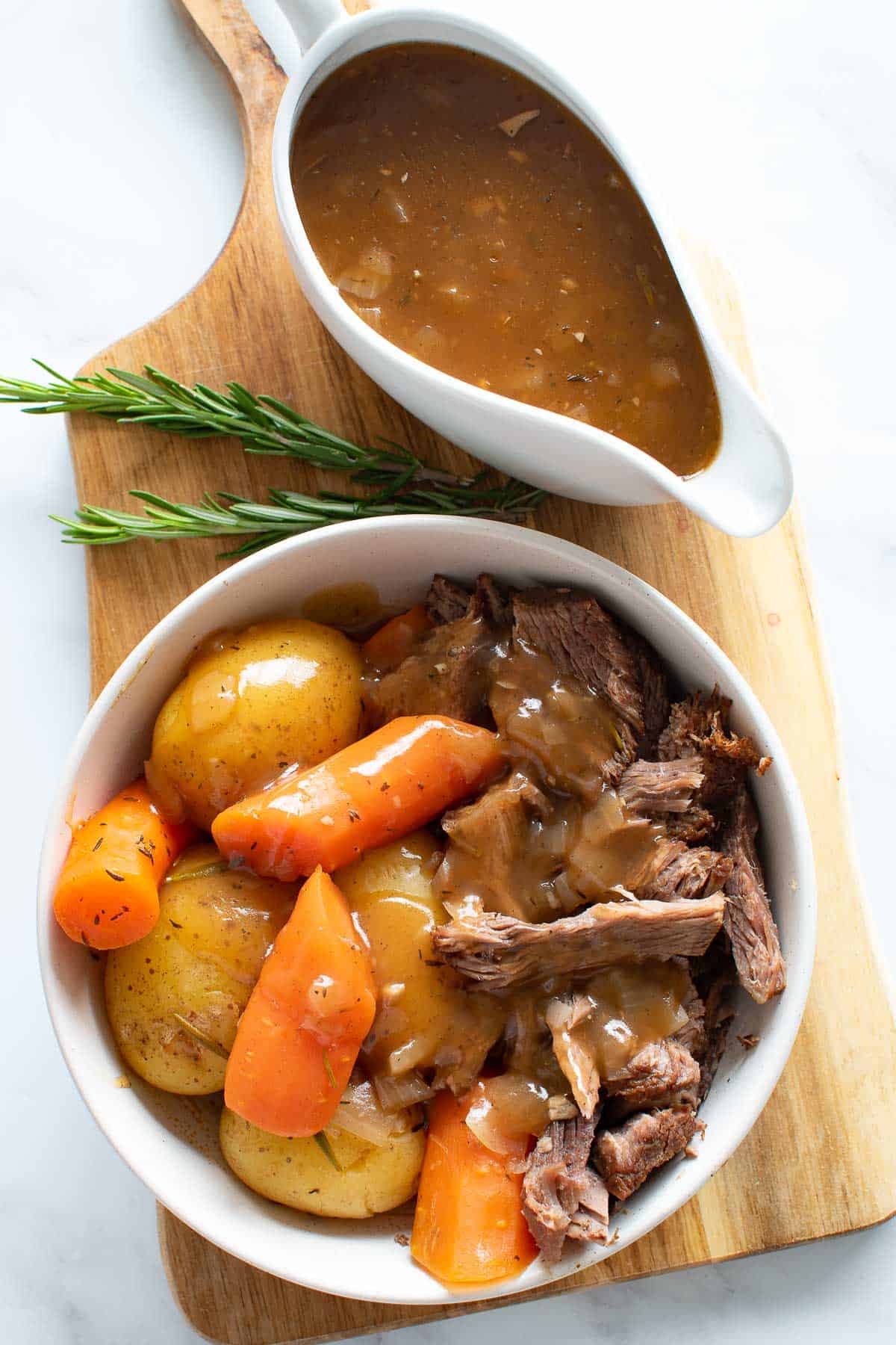 A bowl of instant pot pot roast, with gravy on the side.