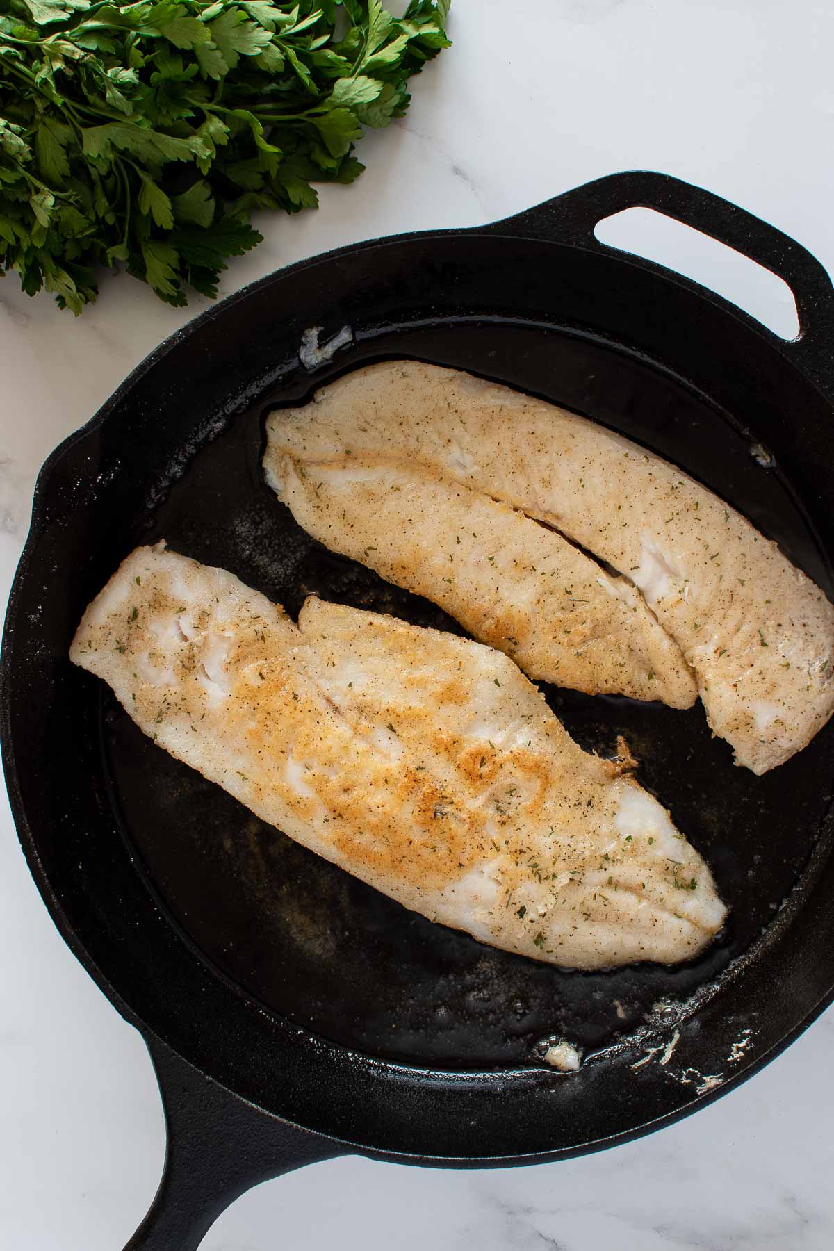 Pan seared hake in a cast iron skillet.