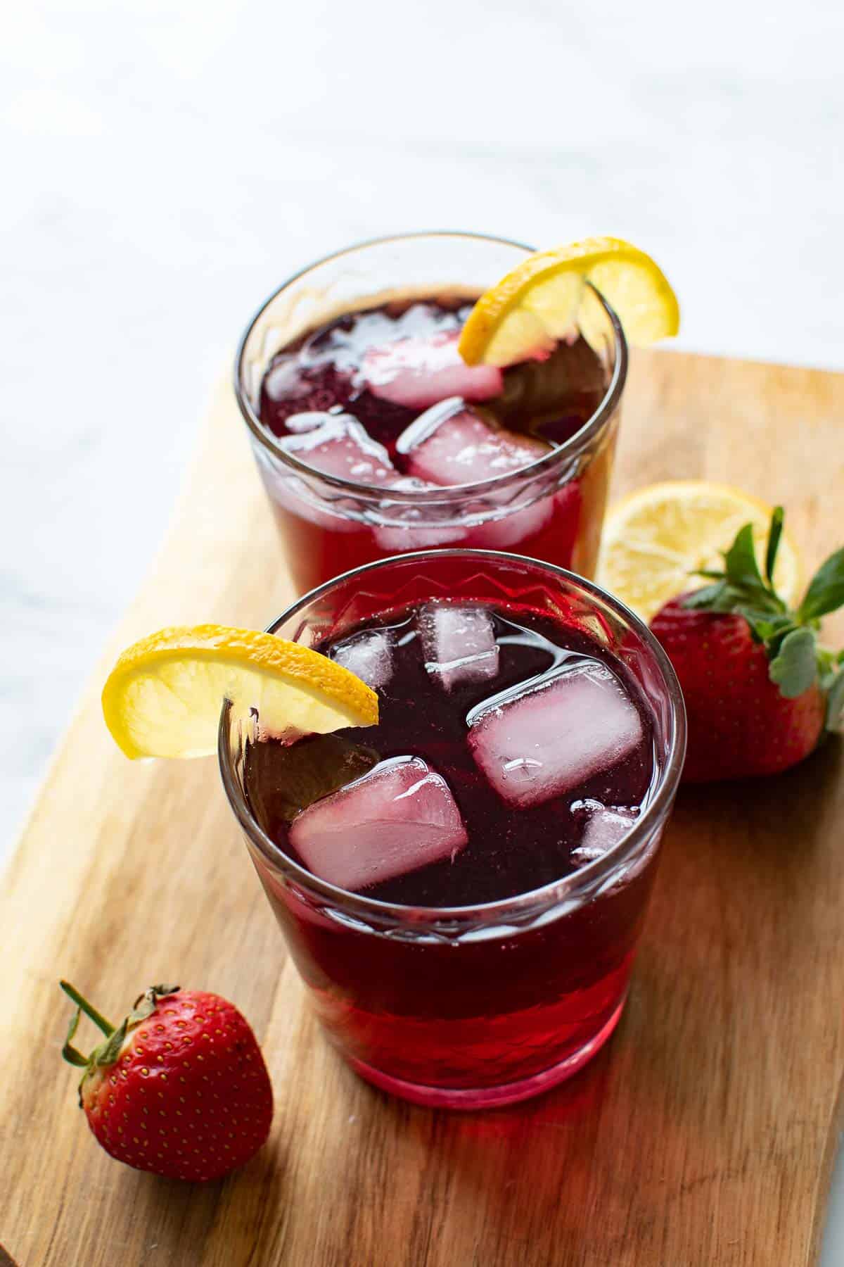 Two glasses of red wine summer cocktails with lemon and ice cubes.