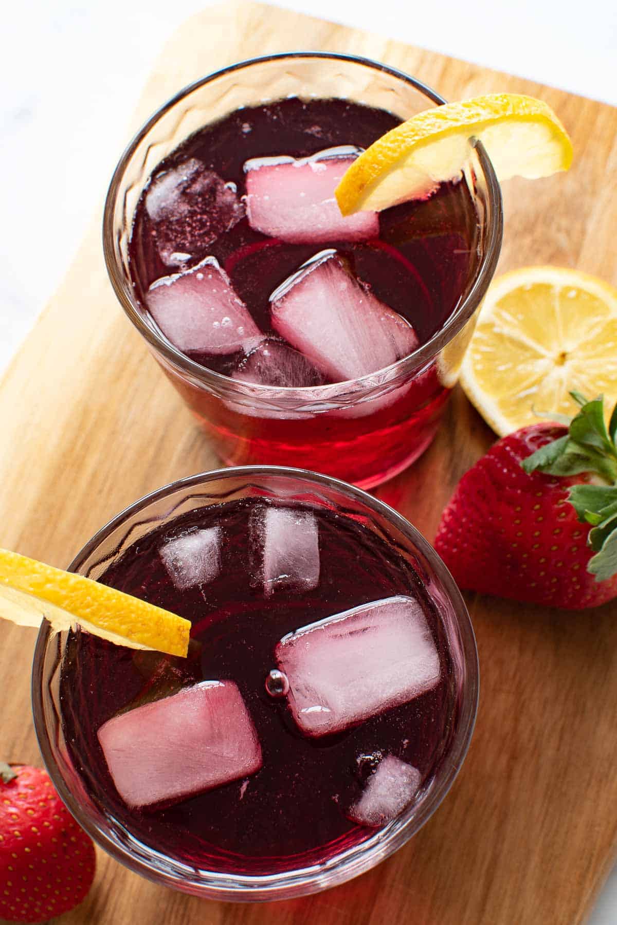 Two glasses of chilled red wine cocktails on a wooden chopping board.