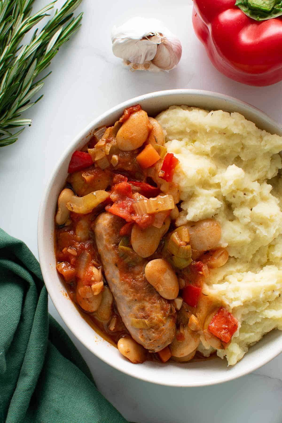 Slow cooker sausage stew and mashed potatoes in a bowl.