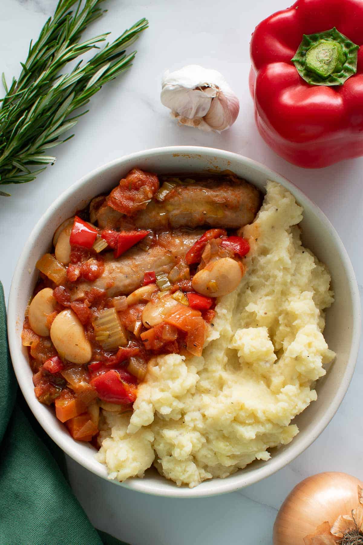 Close up of a bowl with sausage stew with leek, carrot and peppers.