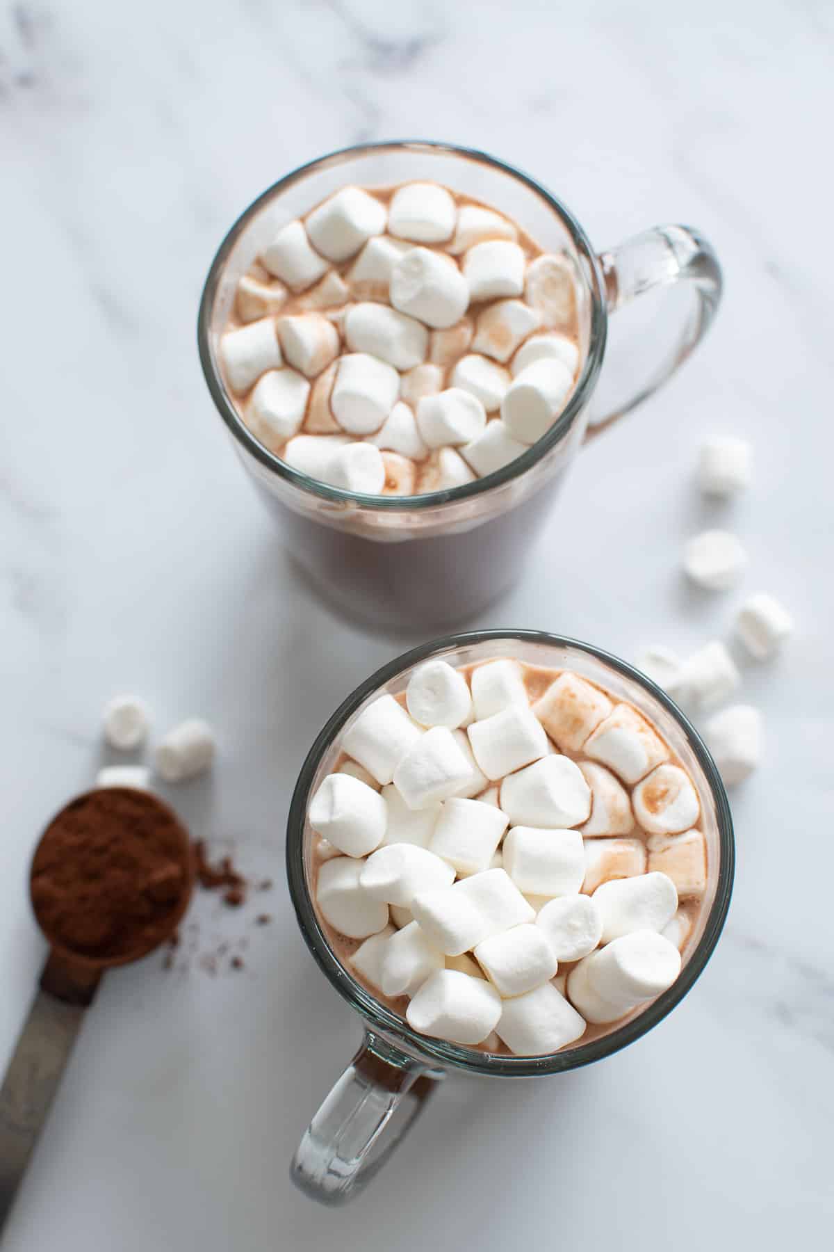 Two cups of sugar free hot chocolate, with a spoon of cocoa powder on the side.