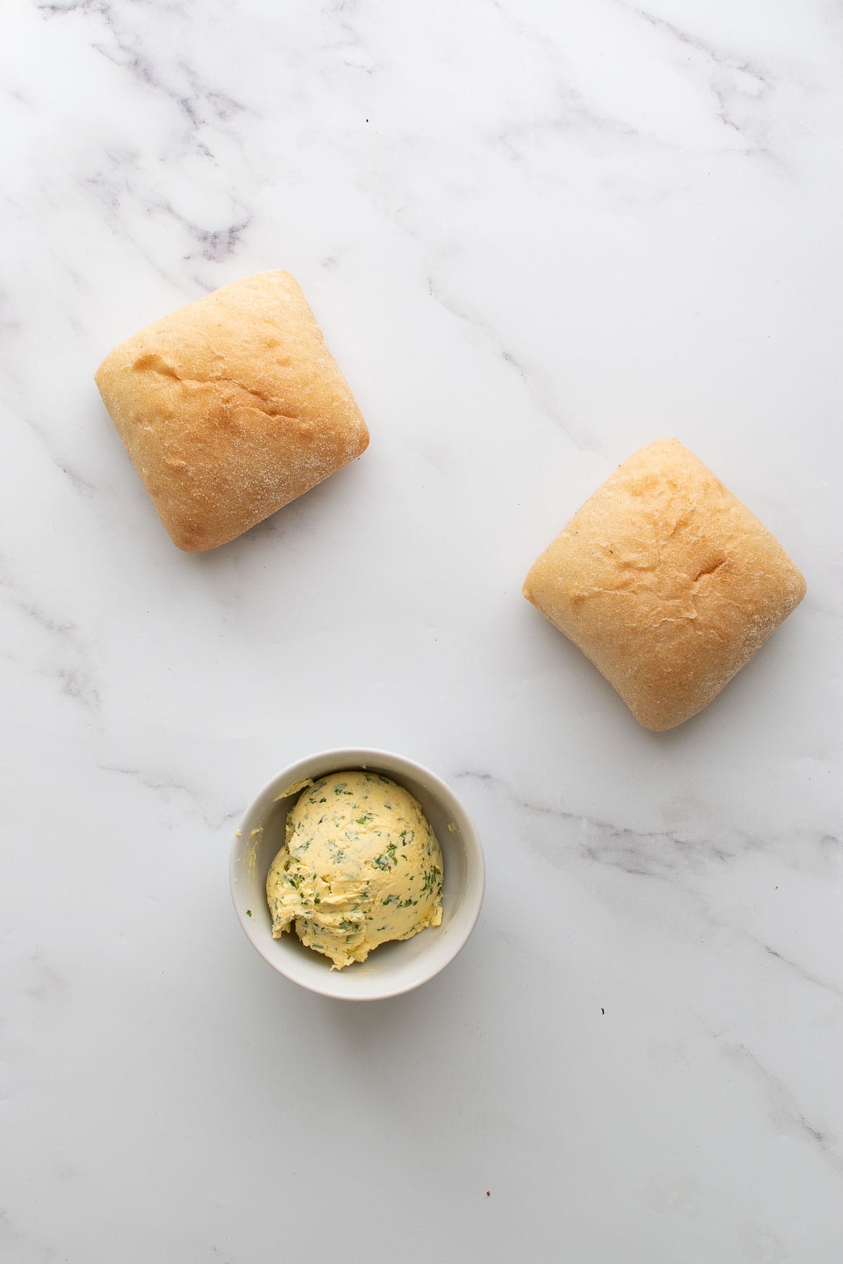 Ciabattas and compound butter on a table.