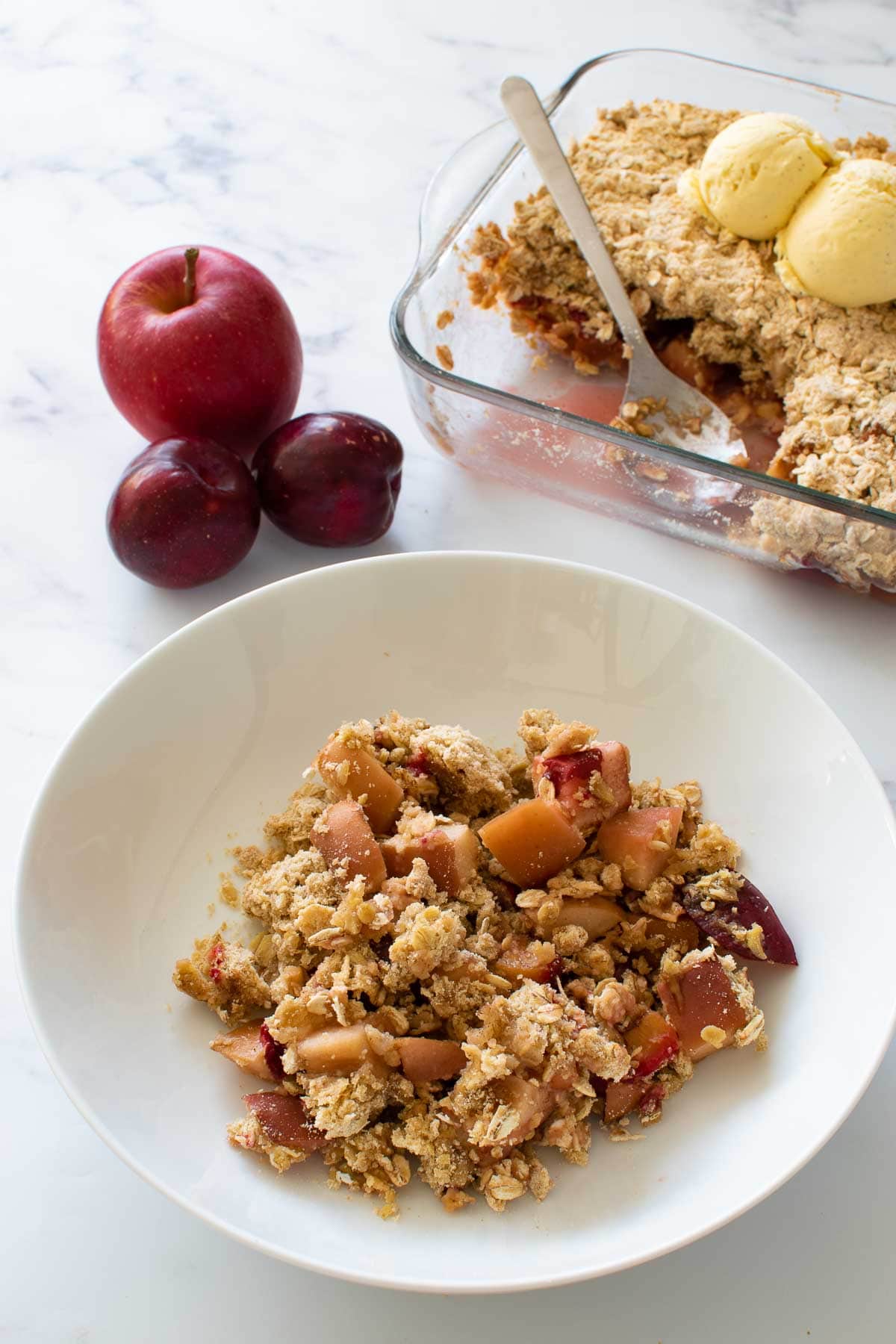 Apple crumble with plums in a bowl.