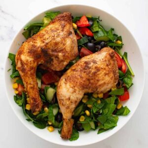 Baked chicken leg quarters with a mixed salad.