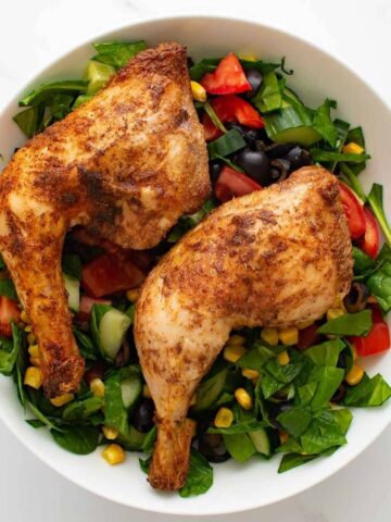 Baked chicken leg quarters with a mixed salad.