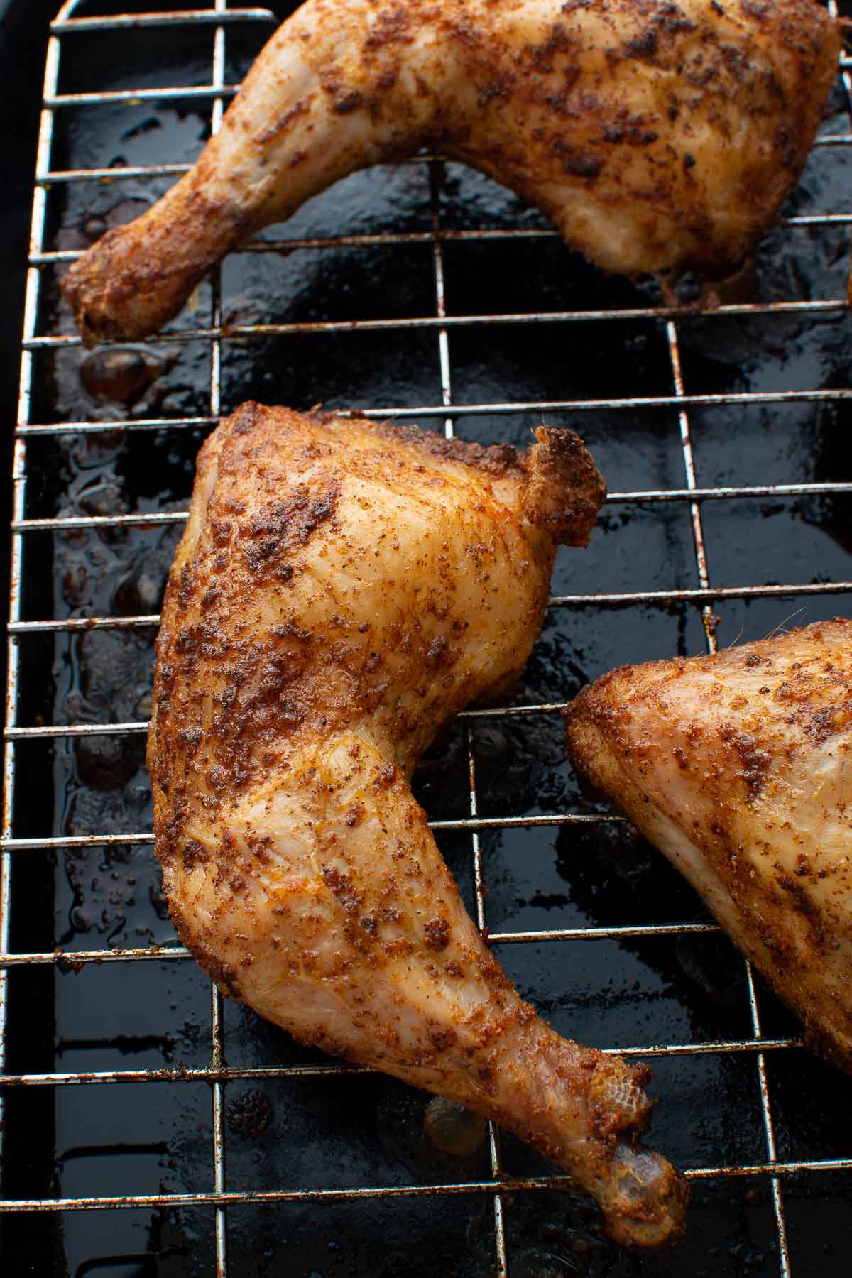 Roasted chicken quarters on a cooling rack.