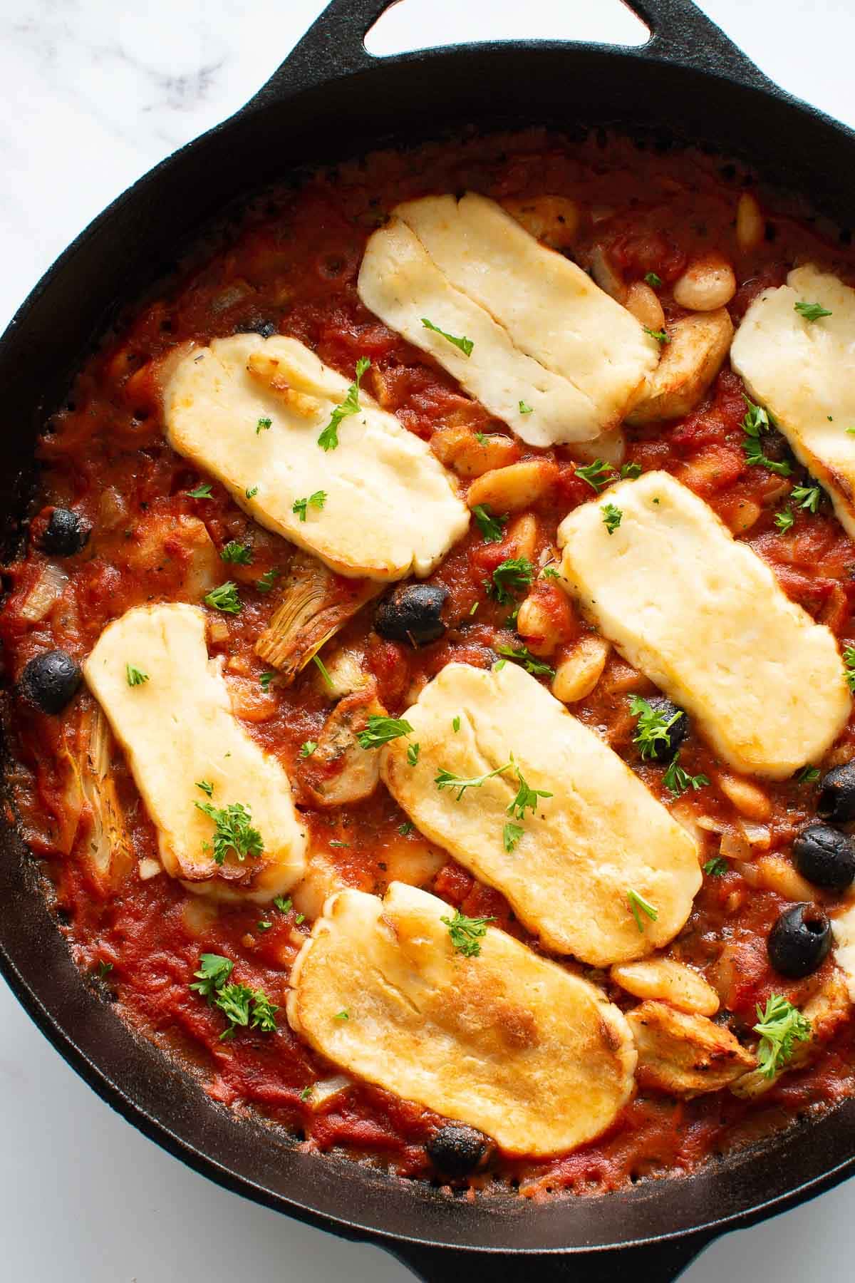 Close up of a cast iron pan with baked halloumi.