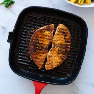 Two blackened swordfish fillets in a grill pan.