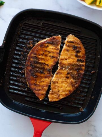 Two blackened swordfish fillets in a grill pan.